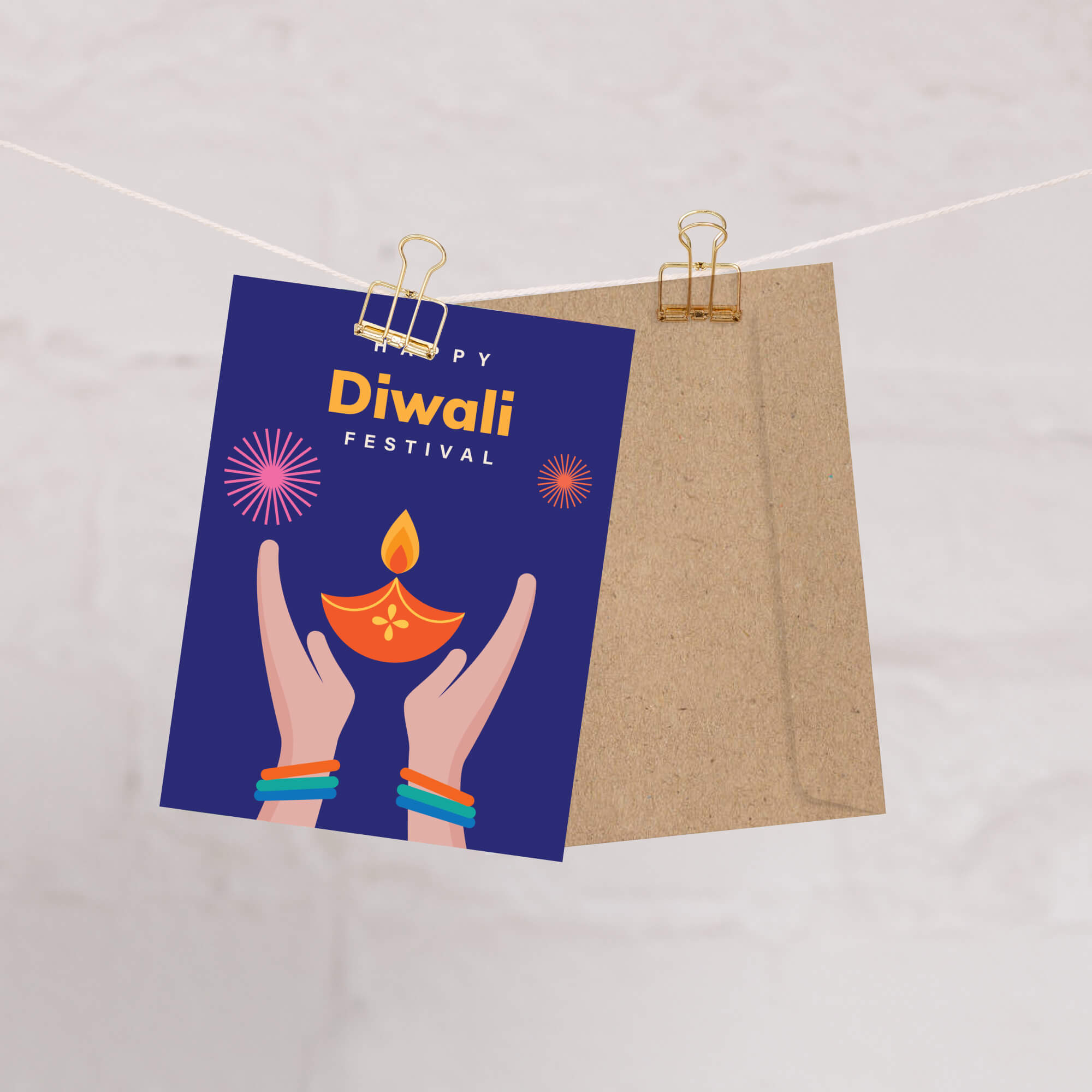 Diwali greeting card with hands holding a lamp and 'Happy Diwali Festival' text on a blue background, clipped to a string.