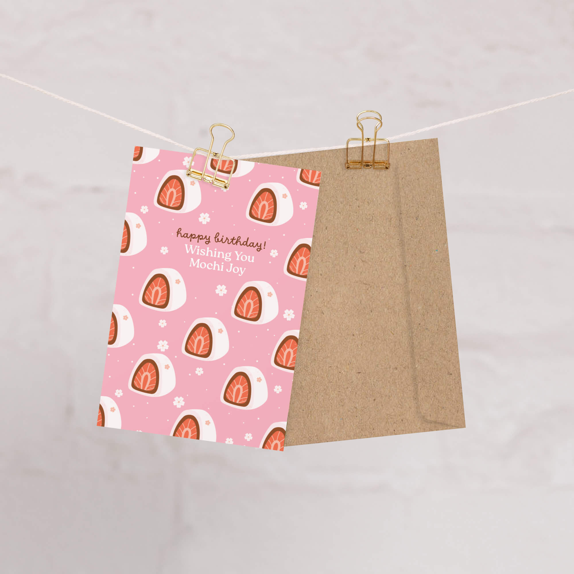 Two pieces of paper with different designs hanging on a string against a light gray background.