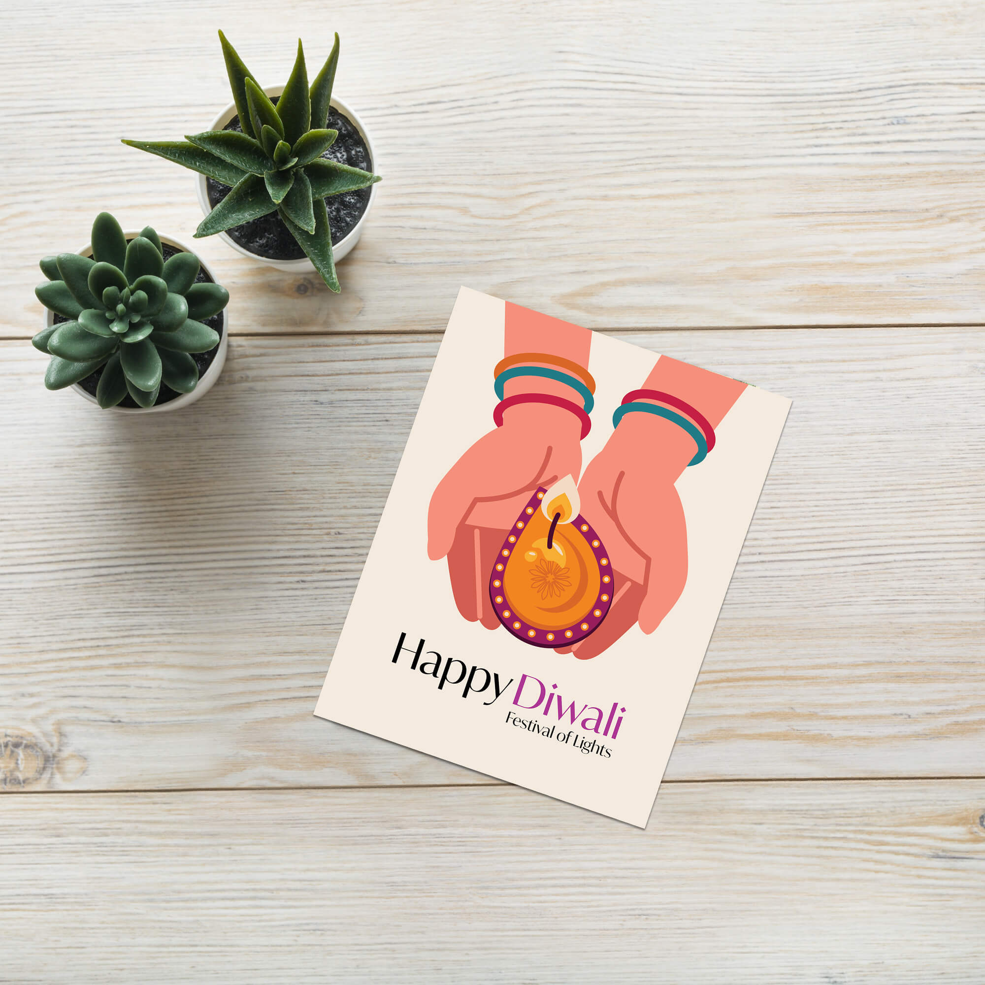 indian Greeting card with 'Happy Diwali' design on a wooden surface with small plants.
