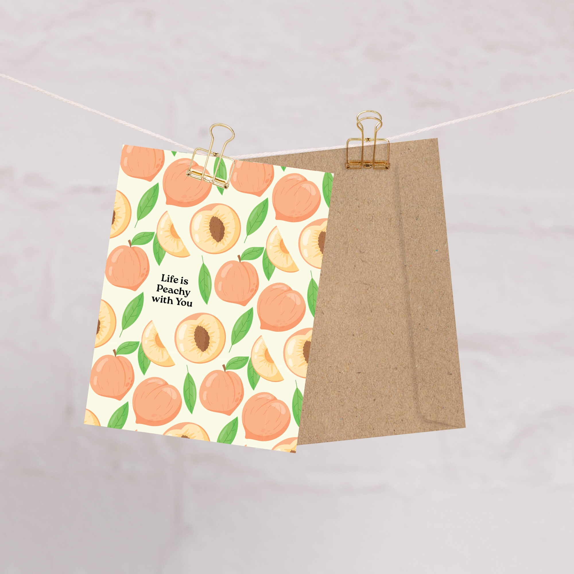Two items hanging on a line with one featuring peaches and the other brown paper.
