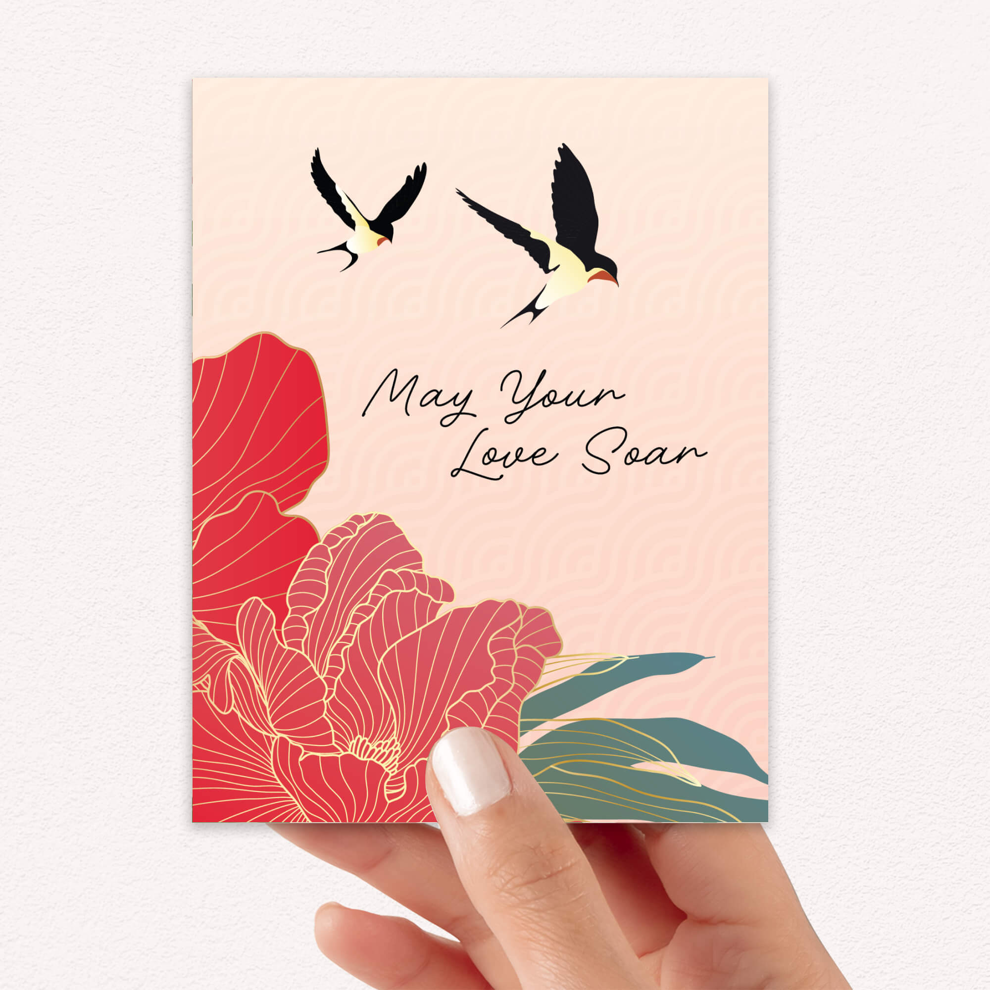 Card with floral design and birds on a pink background, held by a hand.