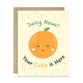 A cute baby shower card with a kraft envelope, featuring a smiling orange illustration and the text 'Juicy News!' and 'Your Cutie is Here' on a cream background.