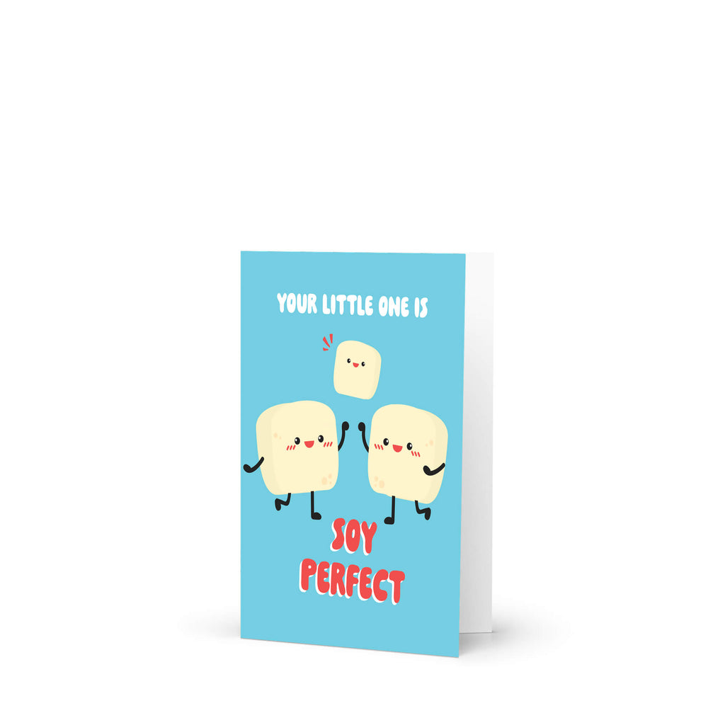 A light blue greeting card with a cute cartoon illustration of three smiling tofus and the text 'YOUR LITTLE ONE IS JOY PERFECT' in white and red, shown standing upright on a white background.