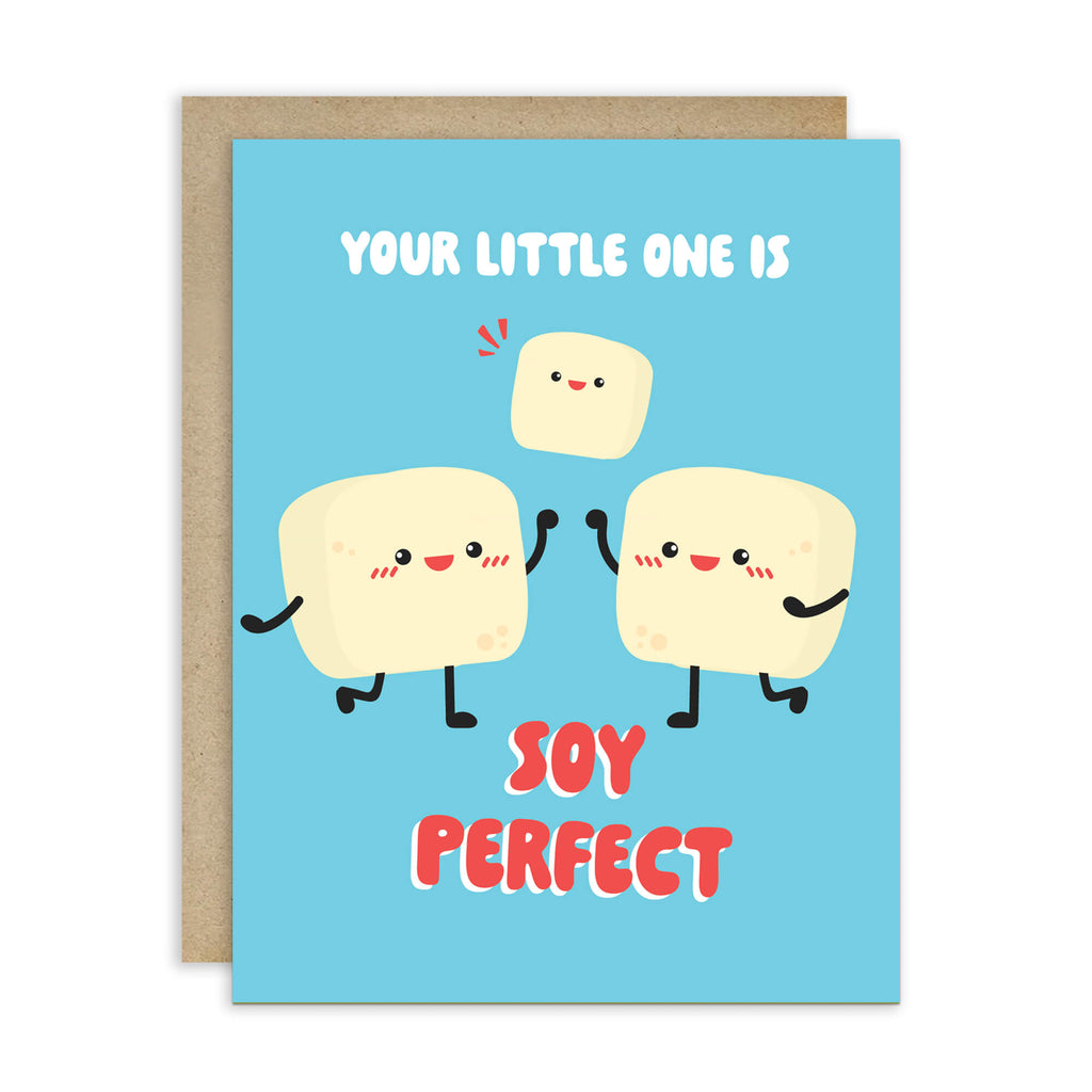 A funny baby shower card with a light blue front and a kraft envelope behind it. The card features a cute cartoon illustration of three smiling tofus holding hands, with the text 'YOUR LITTLE ONE IS' above and 'SOY PERFECT' below in red and white lettering.