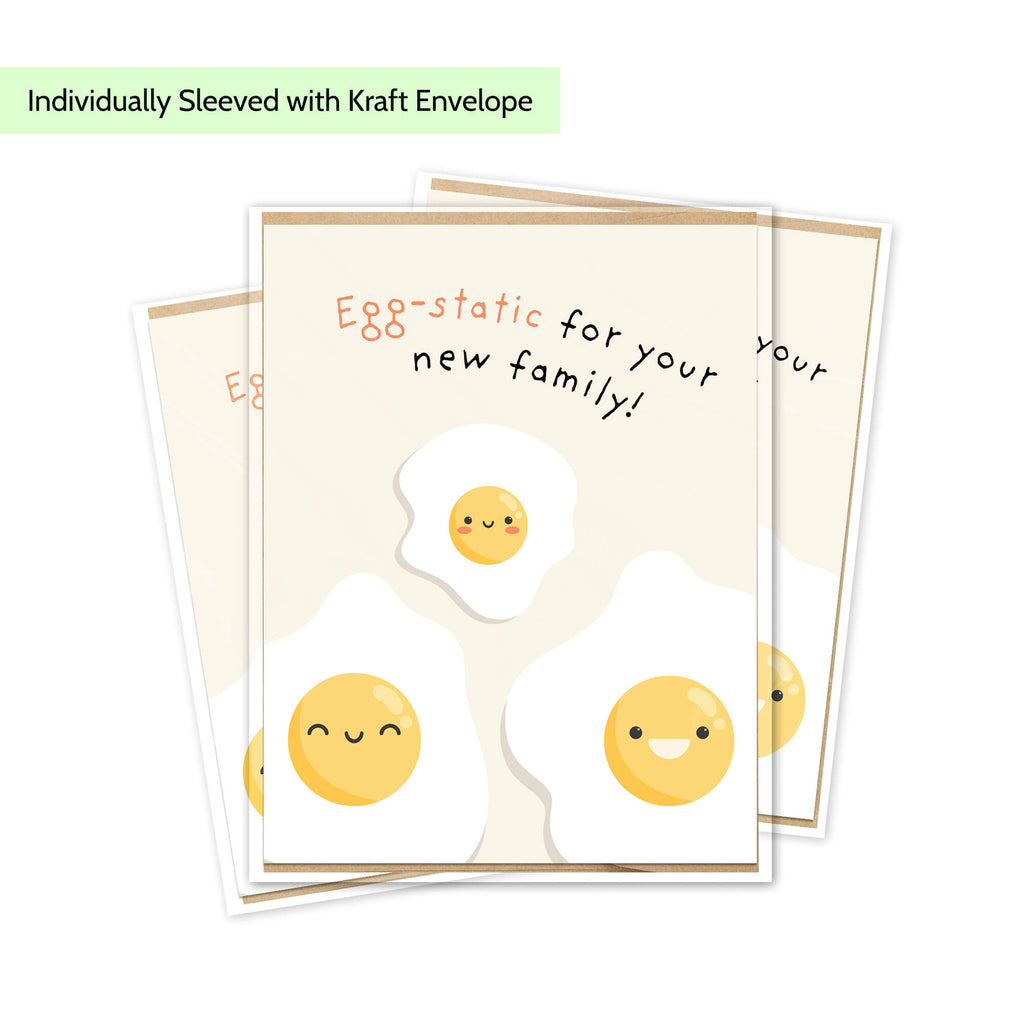A stack of greeting cards with a cute egg-themed design, shown on a white background with a light green text banner at the top that reads 'Individually Sleeved with Kraft Envelope'. The cards feature smiling cartoon fried eggs and the phrase 'Egg-static for your new family!'.