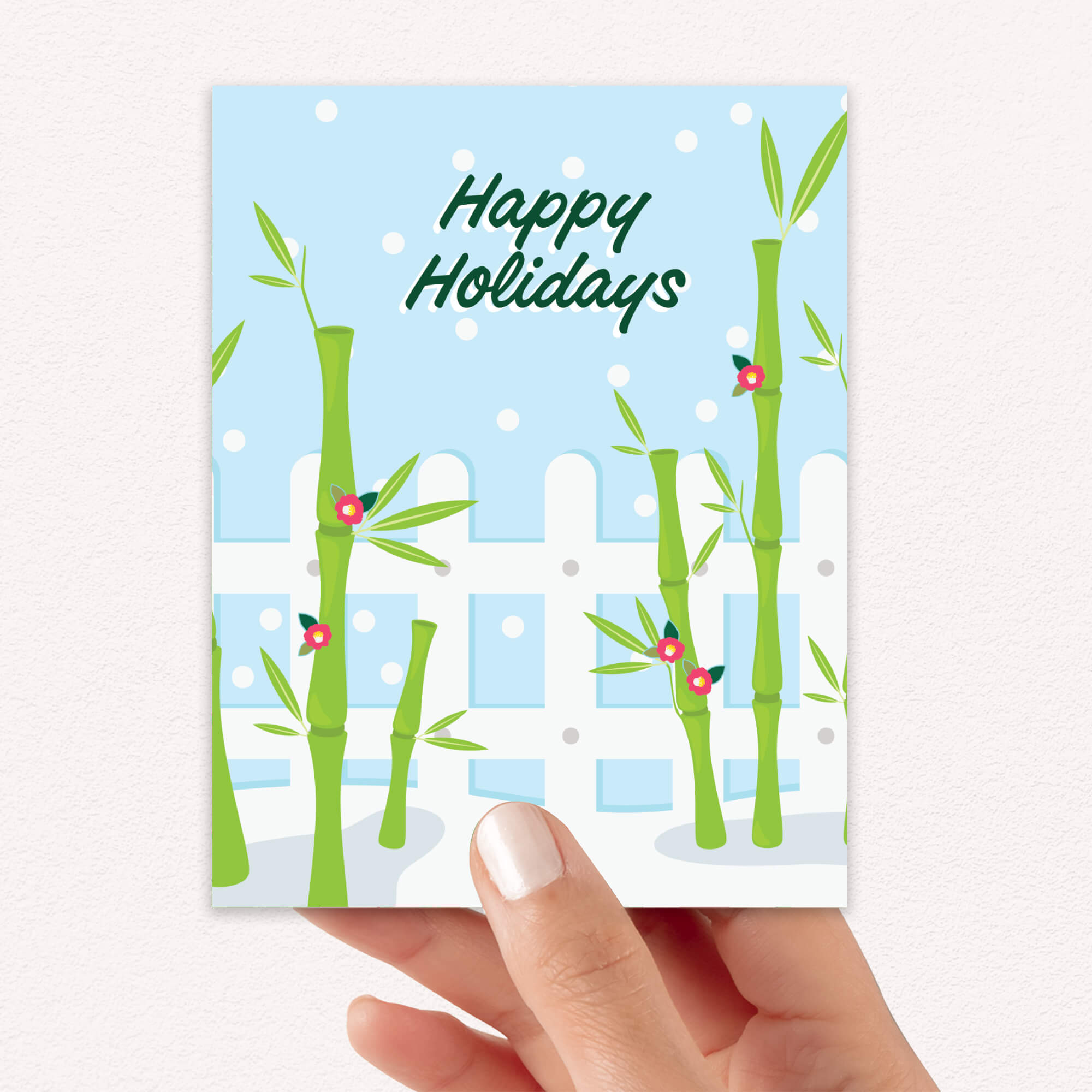Hand holding a card with bamboo design and 'Happy Holidays' text.
