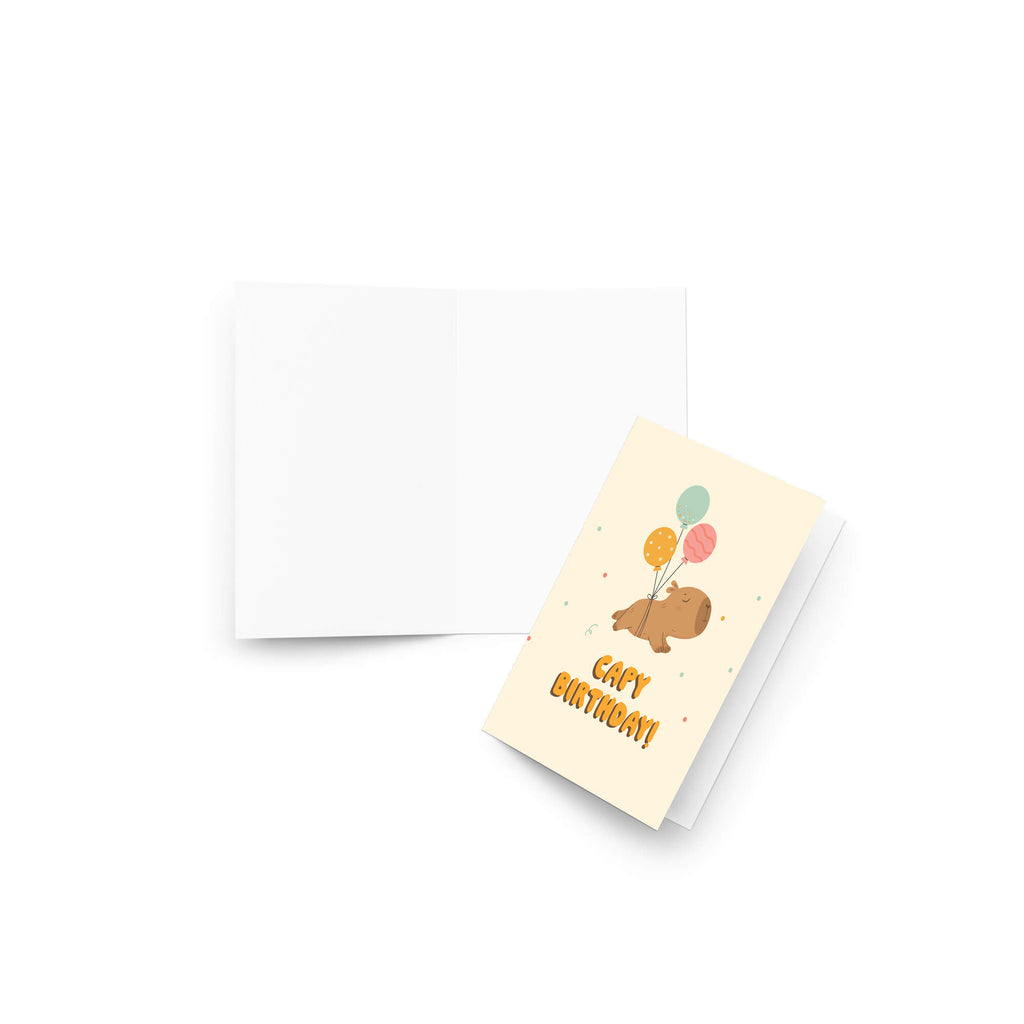 A capybara birthday greeting card with a cute cartoon pig holding balloons and the words 'CUTE BIRTHDAY!' in orange, shown next to its white back on a clean white background.