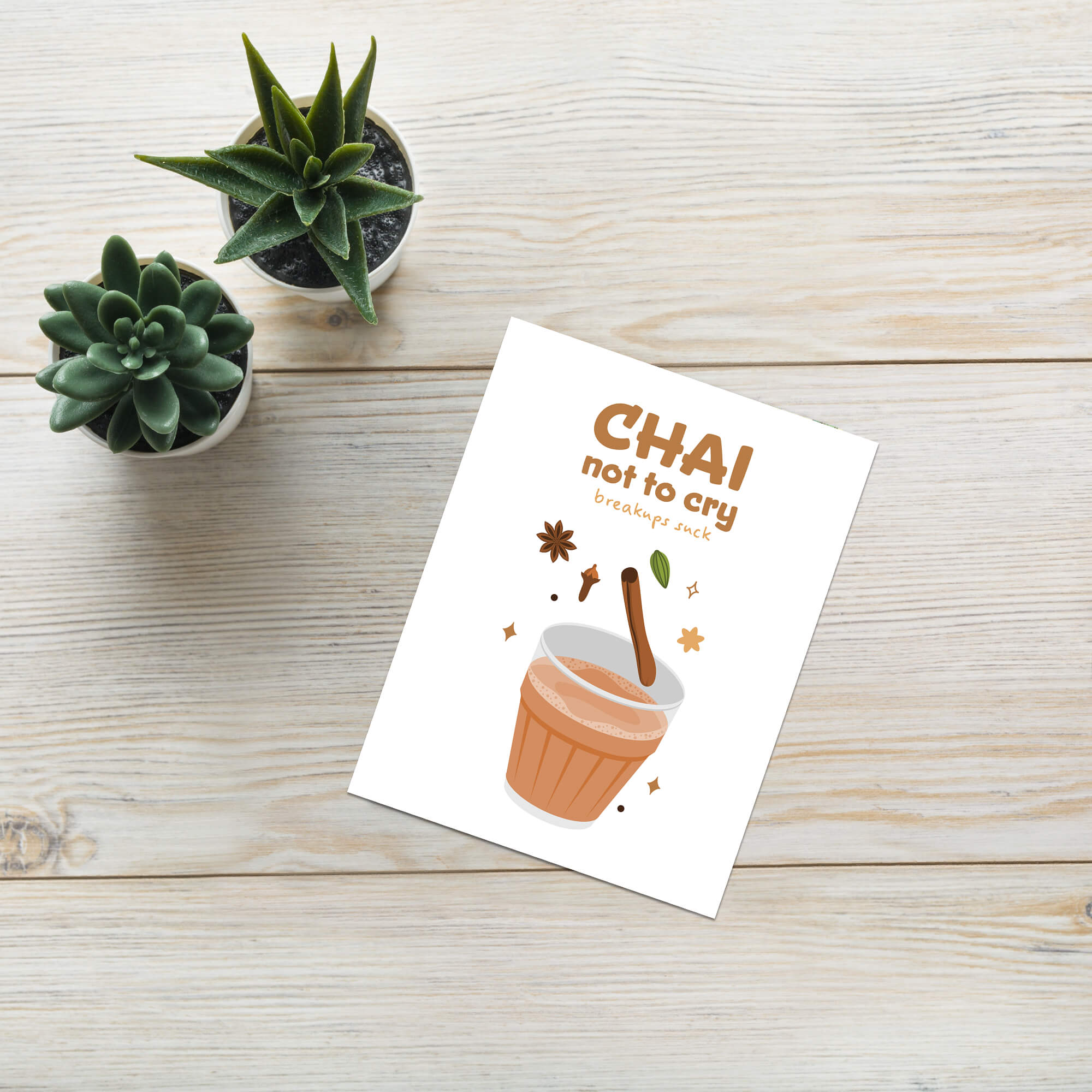 divorce card with 'Chai not to cry' text and cup illustration on a wooden surface with small plants.