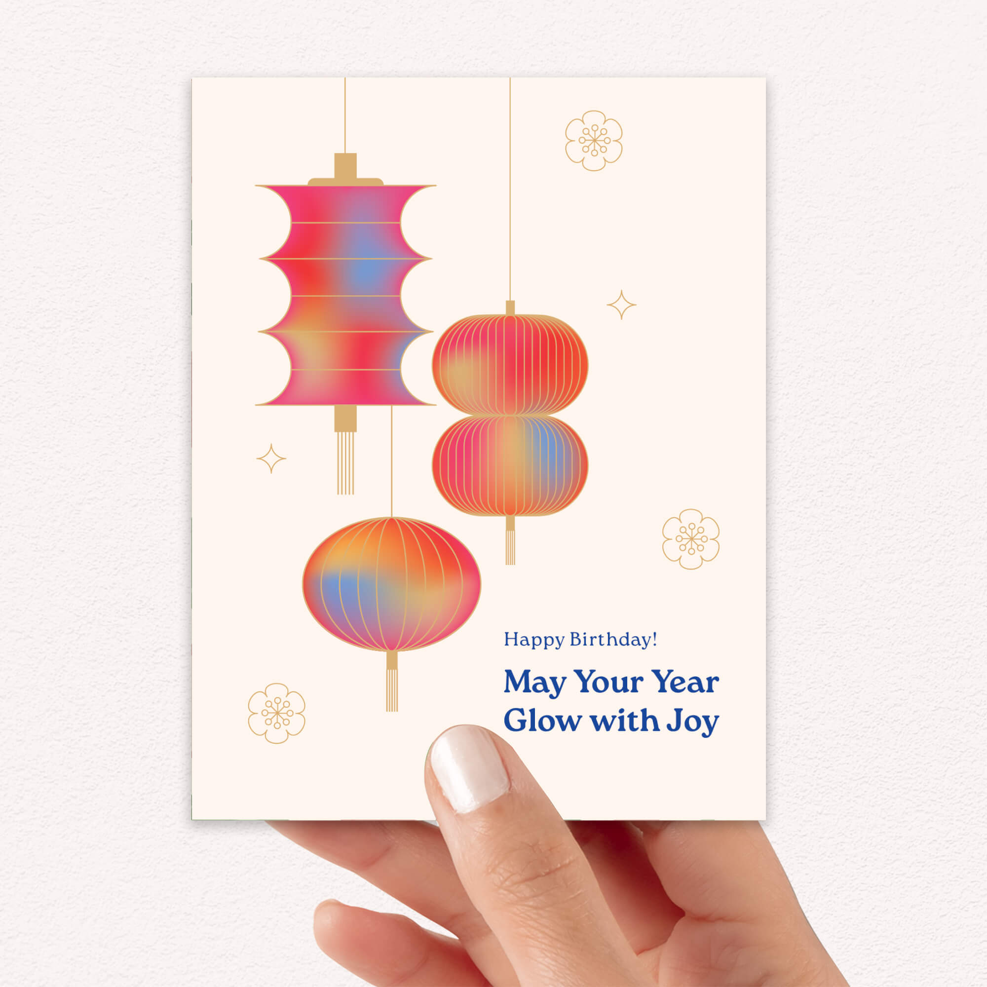 Hand holding a birthday card with colorful lanterns and a message.