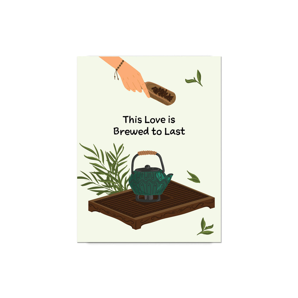 Card with a teapot, hand holding a box, and text 'This Love is Brewed to Last' on a white background.