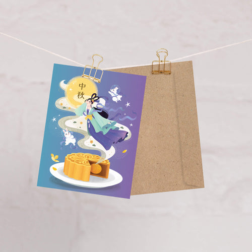 chinese Greeting card with mooncake illustration and traditional Chang E illustration with white jade rabbits and mooncake on a purple background, clipped to a string.