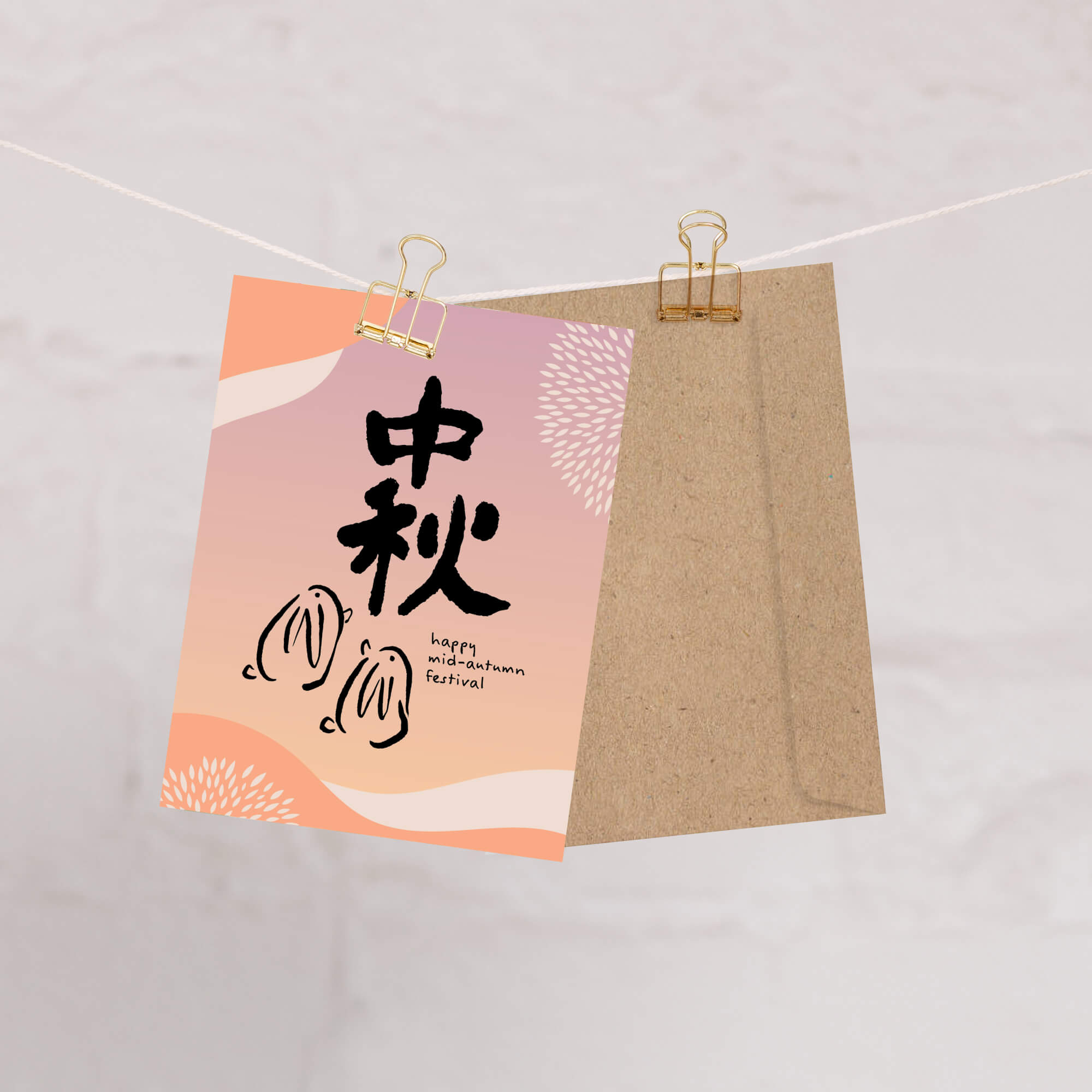 asian greeting Card with 'Happy Mid-Autumn Festival' text and traditional Chinese characters on a pink background, clipped to a string.