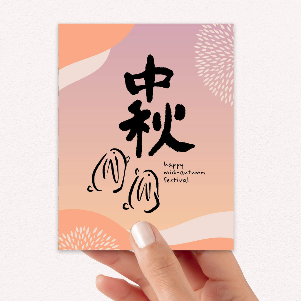 chinese inspired greeting Card with black calligraphy and 'happy mid-autumn festival' text on a pink and orange gradient background.