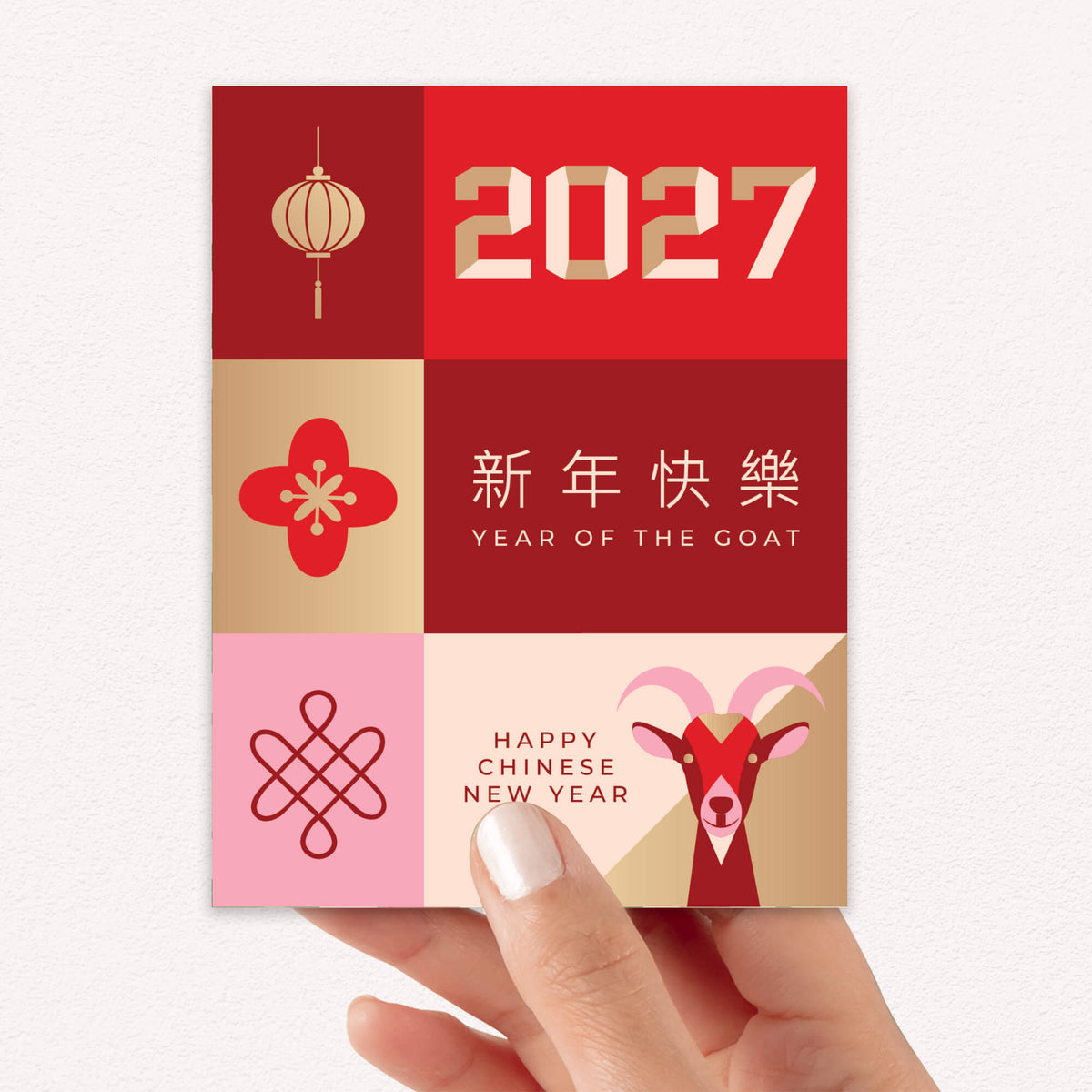 A hand holding a square Lunar New Year greeting card featuring a red and gold 2027 design, with the text '2027', 'YEAR OF THE GOAT', Chinese characters, and a goat illustration on a light textured background.