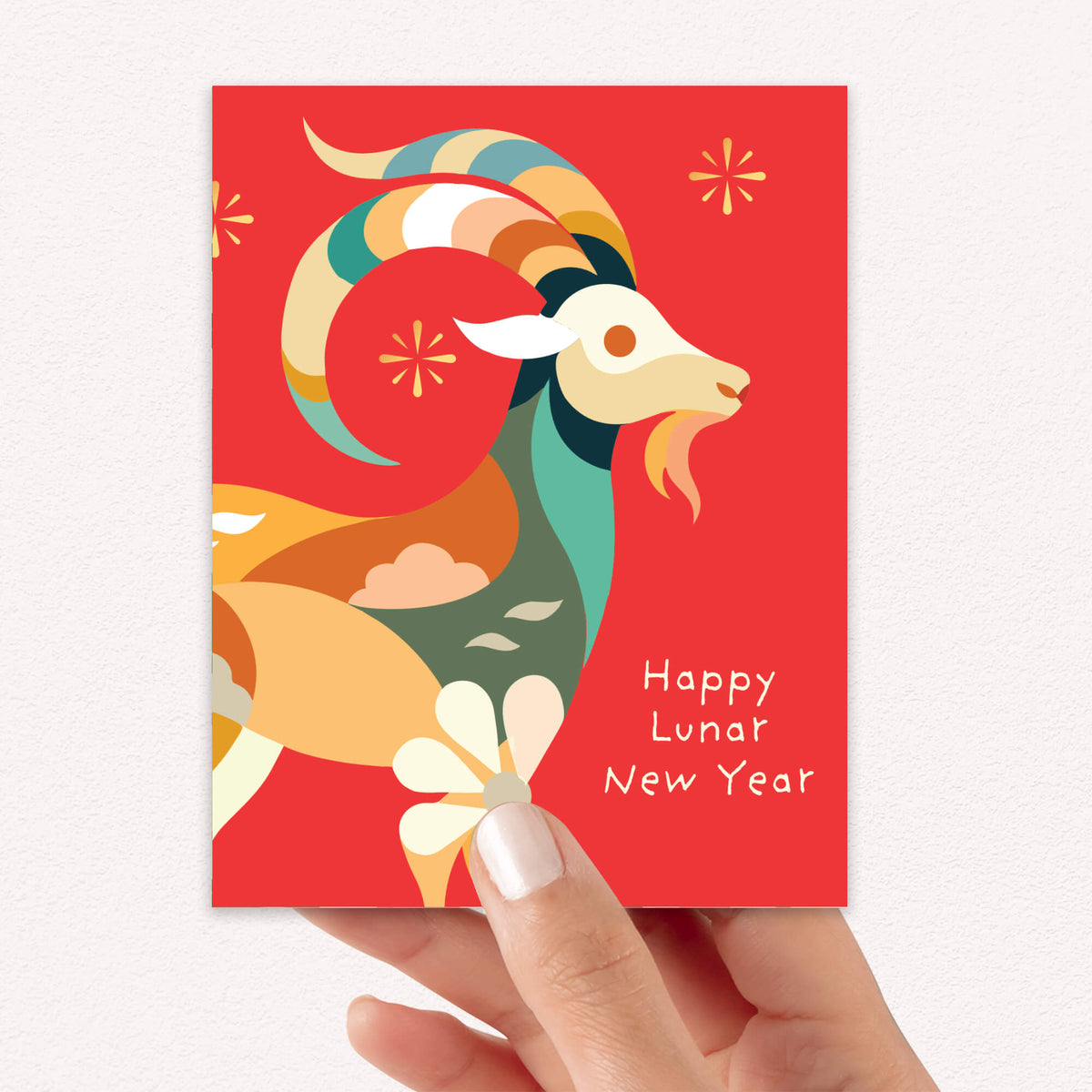 A hand holding a red Lunar New Year greeting card featuring a stylized ram illustration and the text 'Happy Lunar New Year'.