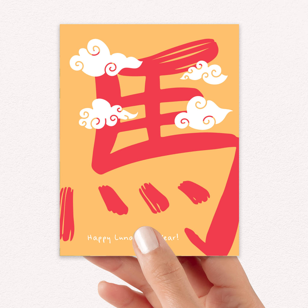 Hand holding a card with red Chinese characters and clouds on an orange background
