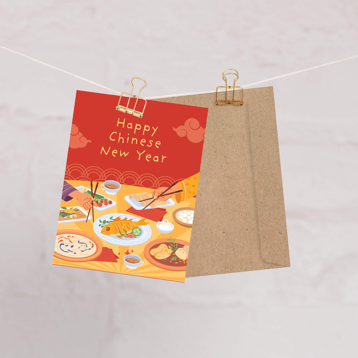 A Chinese New Year card, clipped to a string with a kraft paper envelope behind it, on a light marble background.