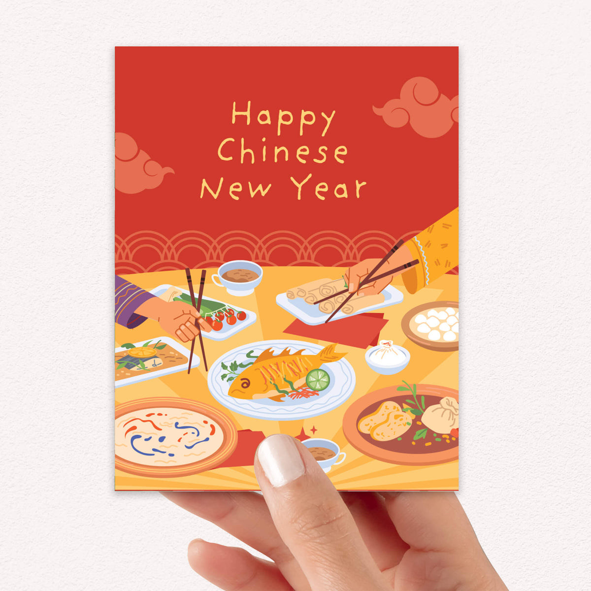 A hand holding a red chinese new year card with a red and yellow illustration of a Chinese New Year table, featuring the text 'Happy Chinese New Year' and food dishes.