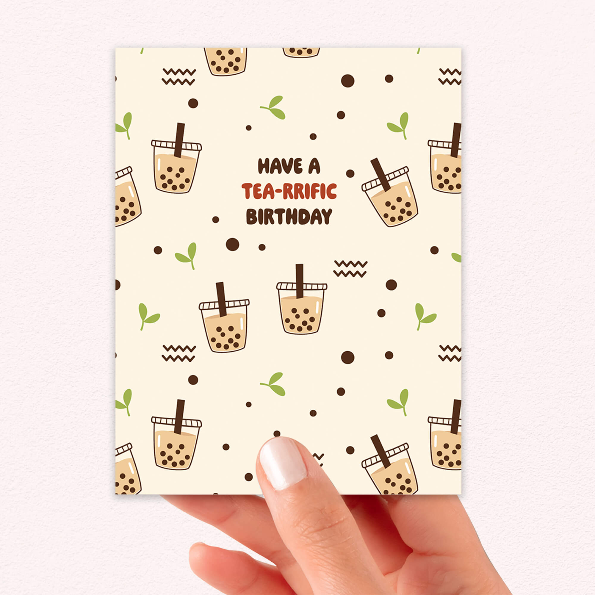 Card with bubble tea design and 'Have a Tea-rrific Birthday' text held by a hand.