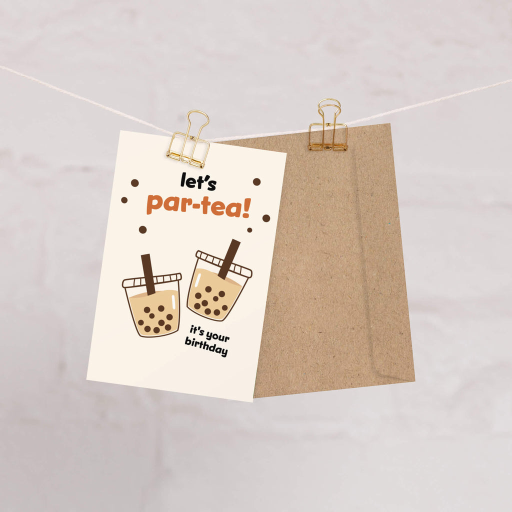 Card with 'let's par-tea! It's your birthday' text and illustrations of bubble tea, clipped to a string.