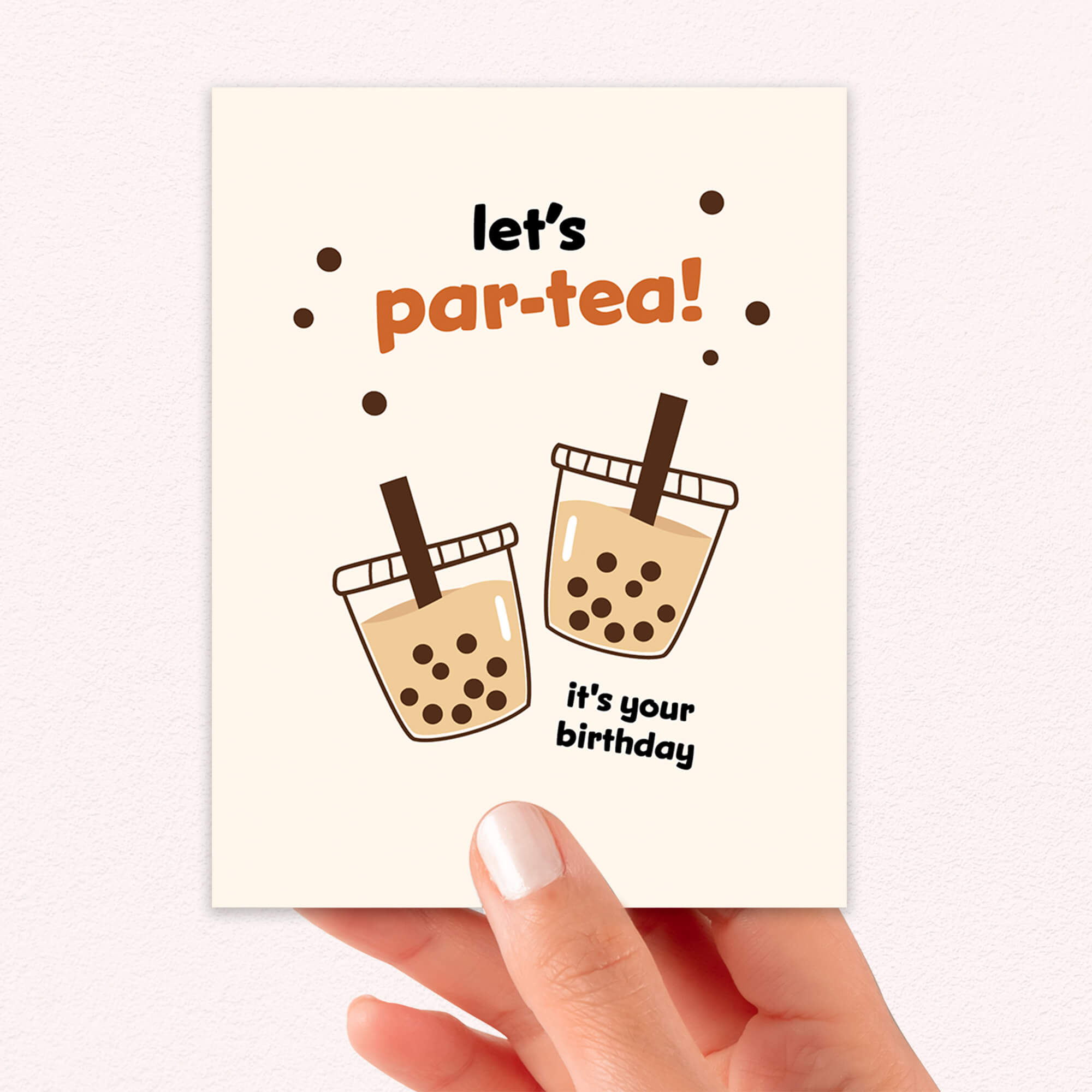 Greeting card with bubble tea design and text 'let's par-tea! it's your birthday' held by a hand.