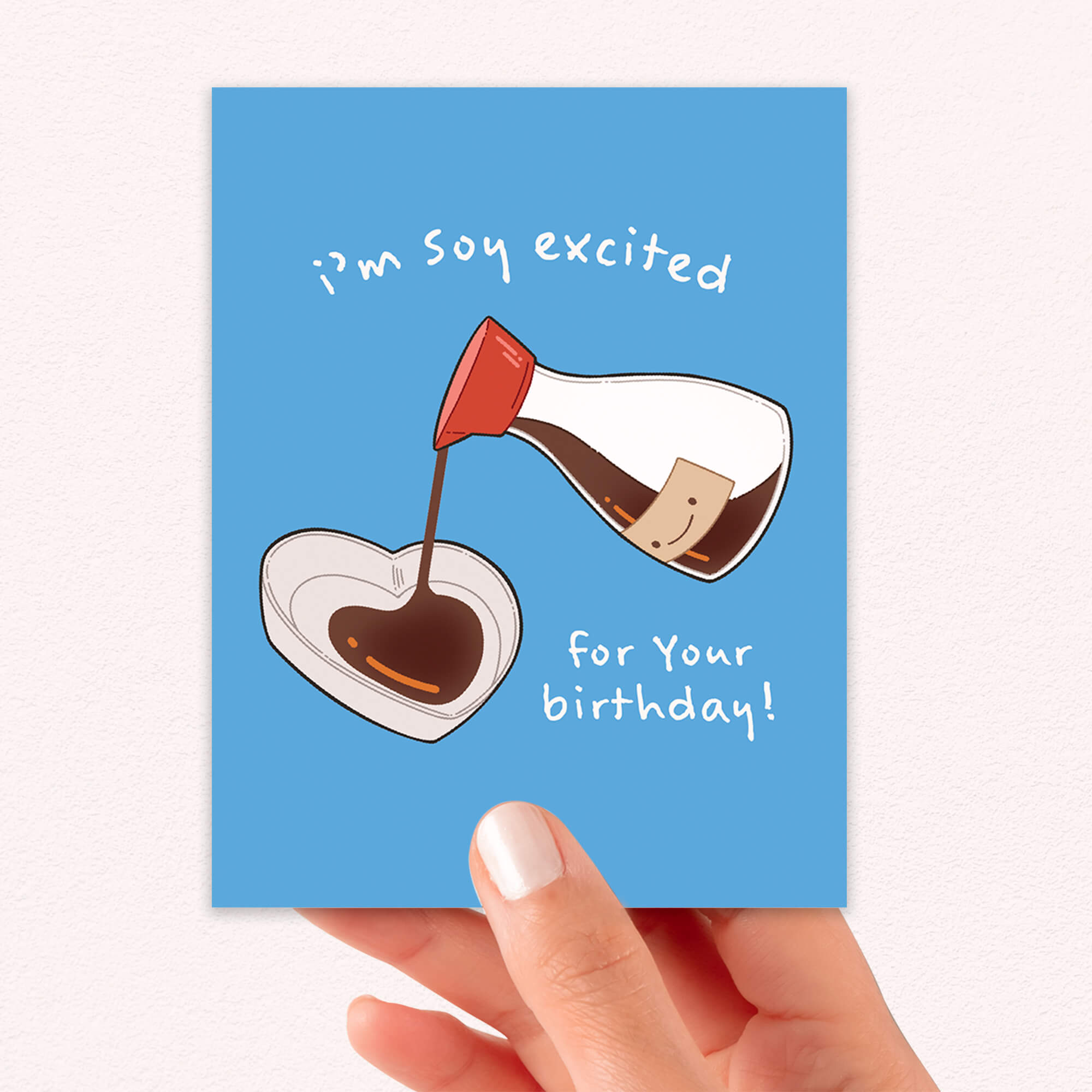 Greeting card with cartoon soy sauce bottle and bowl on a blue background, held by a hand.