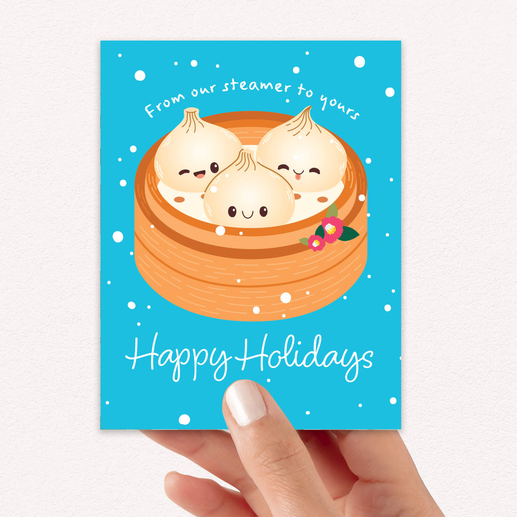 cute christmas greeting card with Three cute soup dumplings in bamboo steamer on teal snow with “From our steamer to yours. Happy Holidays.”