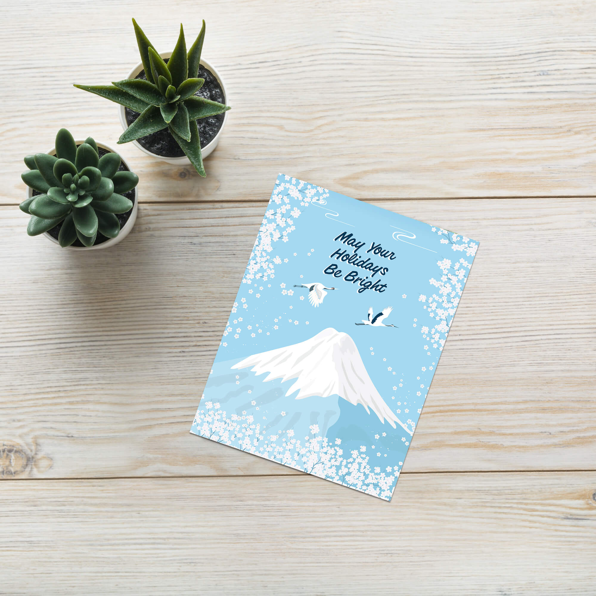 japanese christmas card with a winter snowy Mount Fuji with cranes and white cherry blossoms; text “May Your Holidays Be Bright.”