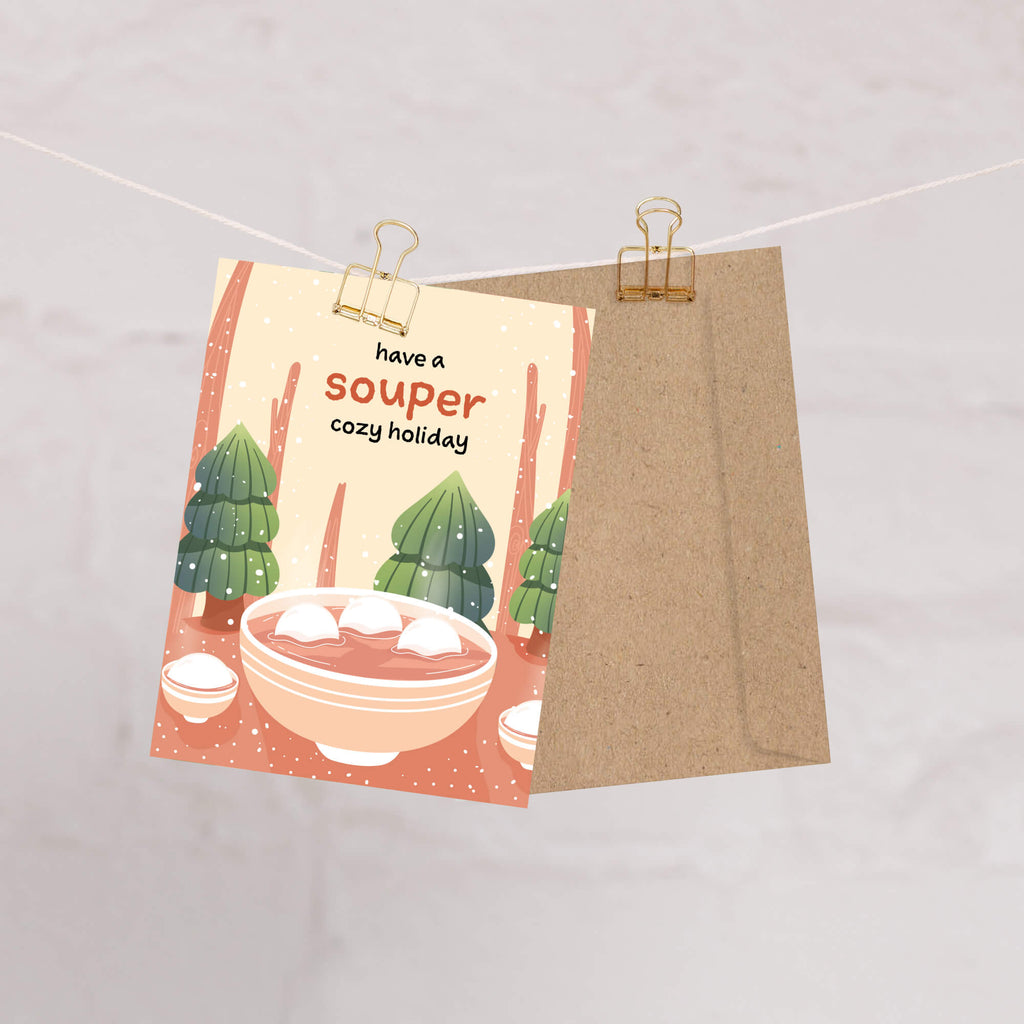 unique holiday Greeting card with a bowl of soup and winter scene, text 'have a souper cozy holiday'. 