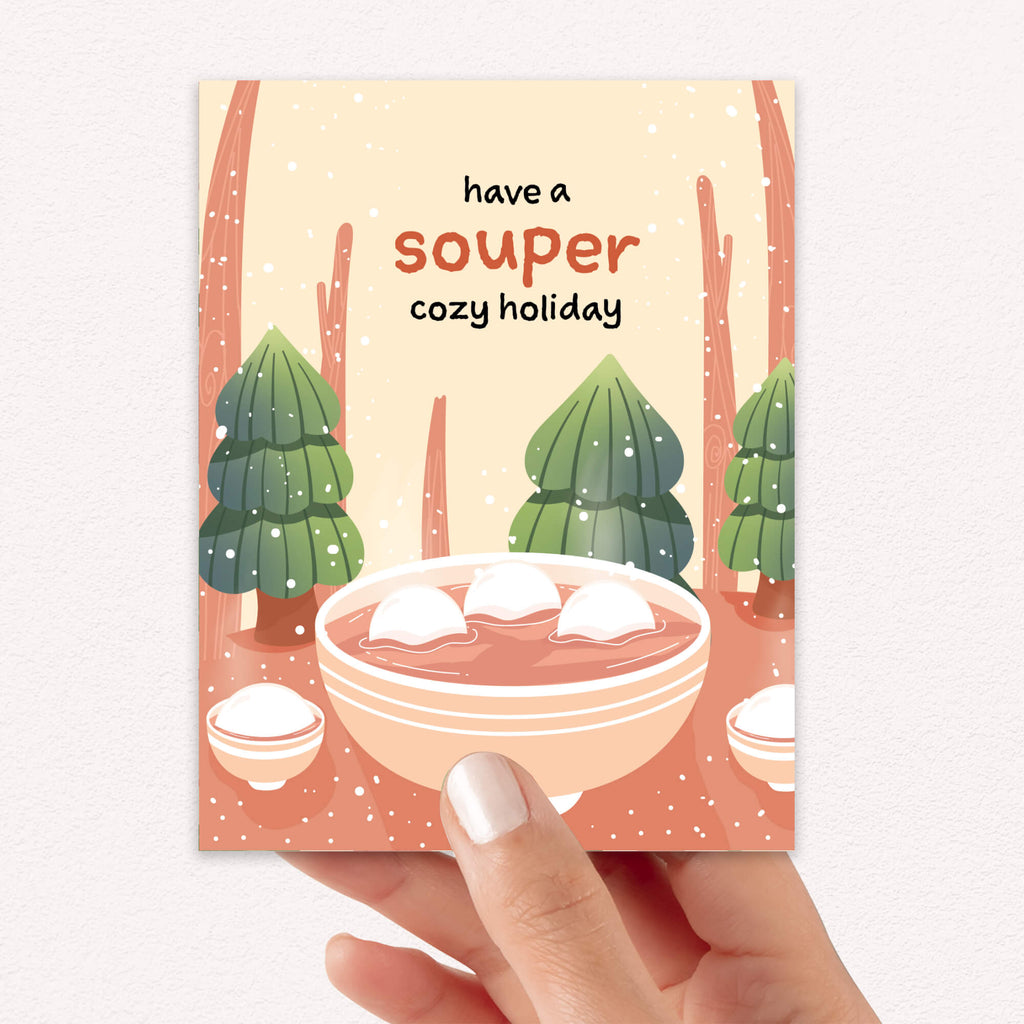 unique holiday Greeting card with a bowl of soup and winter scene, text 'have a souper cozy holiday'. 