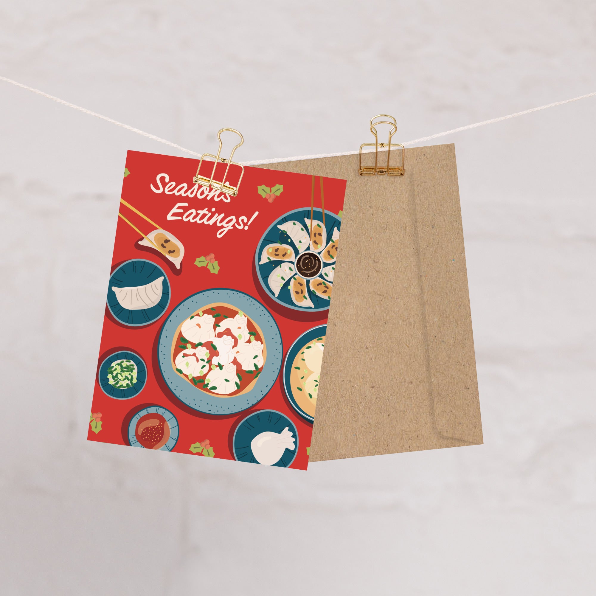 cute christmas card showing a red table with plates of dumplings and sauces, text “Season’s Eatings!”