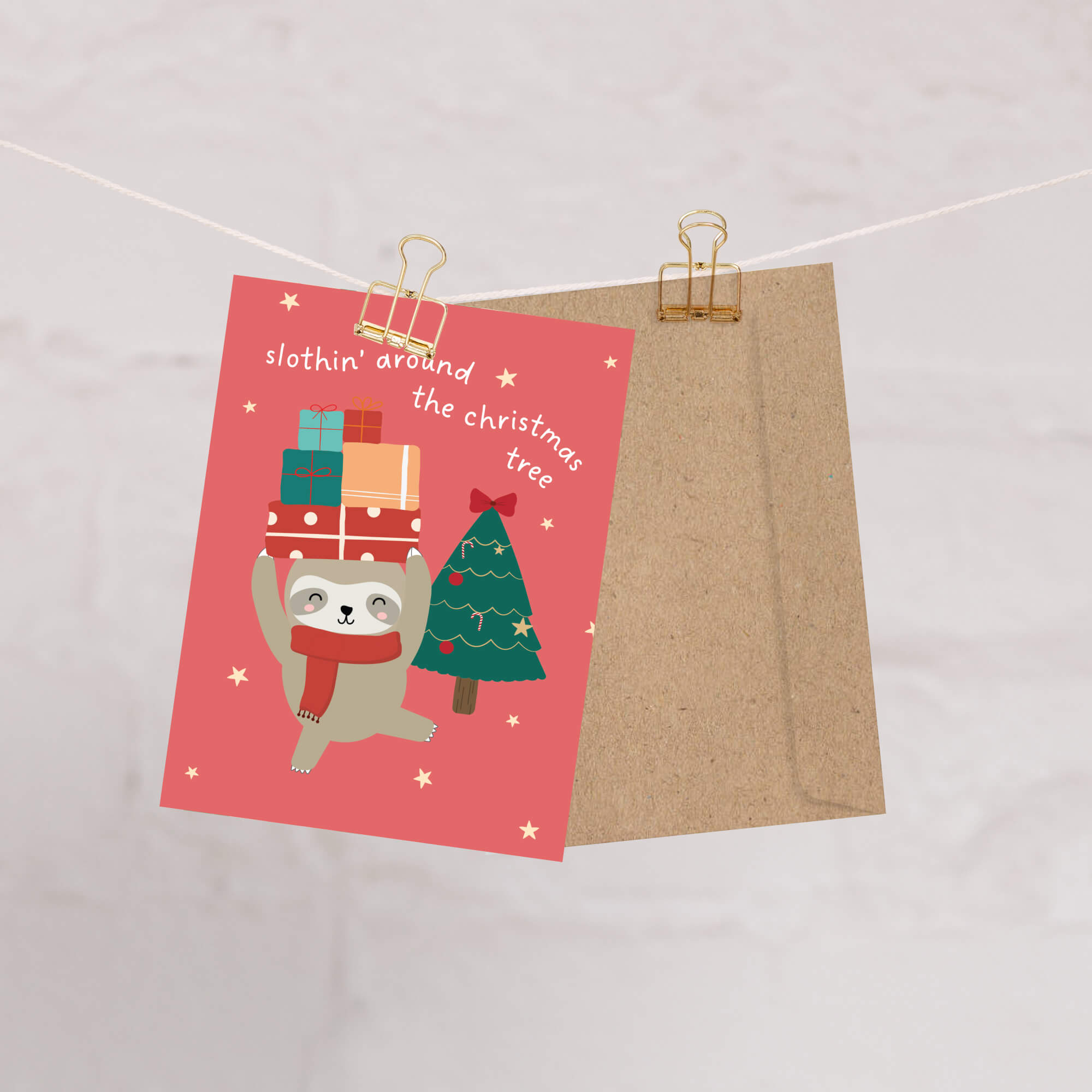 unique Christmas card with a sloth carrying presents and a holiday tree on a red background with text "slothin' around the christmas tree"