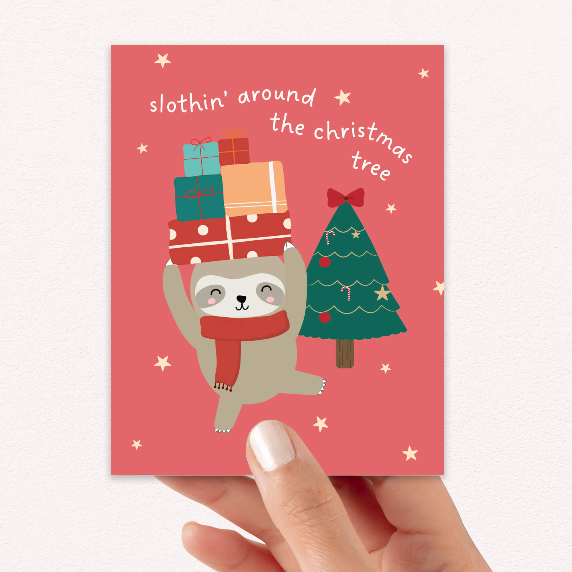 unique Christmas card with a sloth carrying presents and a holiday tree on a red background with text "slothin' around the christmas tree"