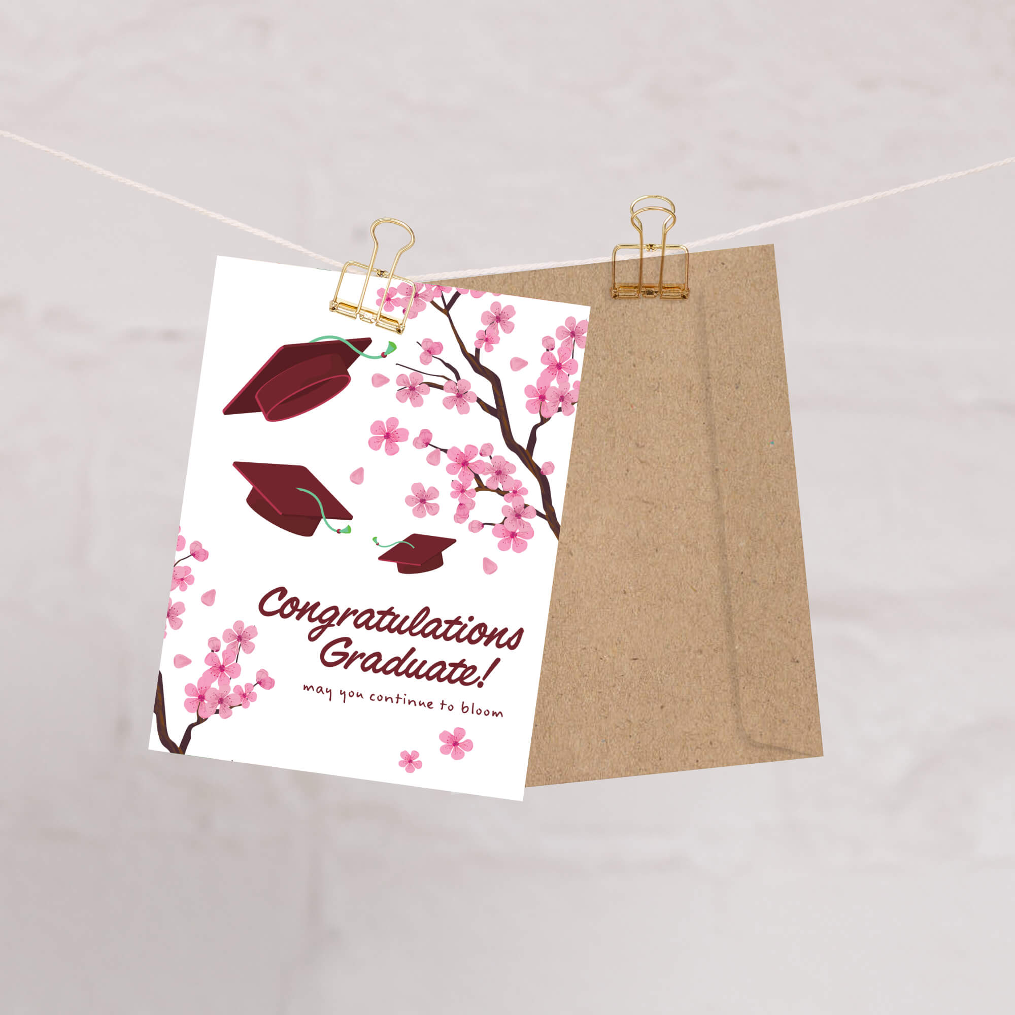 Graduation card with japanese cherry blossoms and red graduation caps on a white background