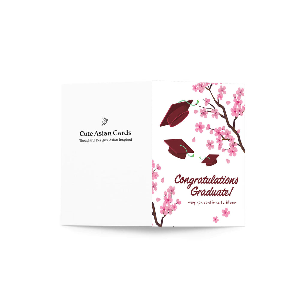 Graduation card with japanese cherry blossoms and red graduation caps on a white background