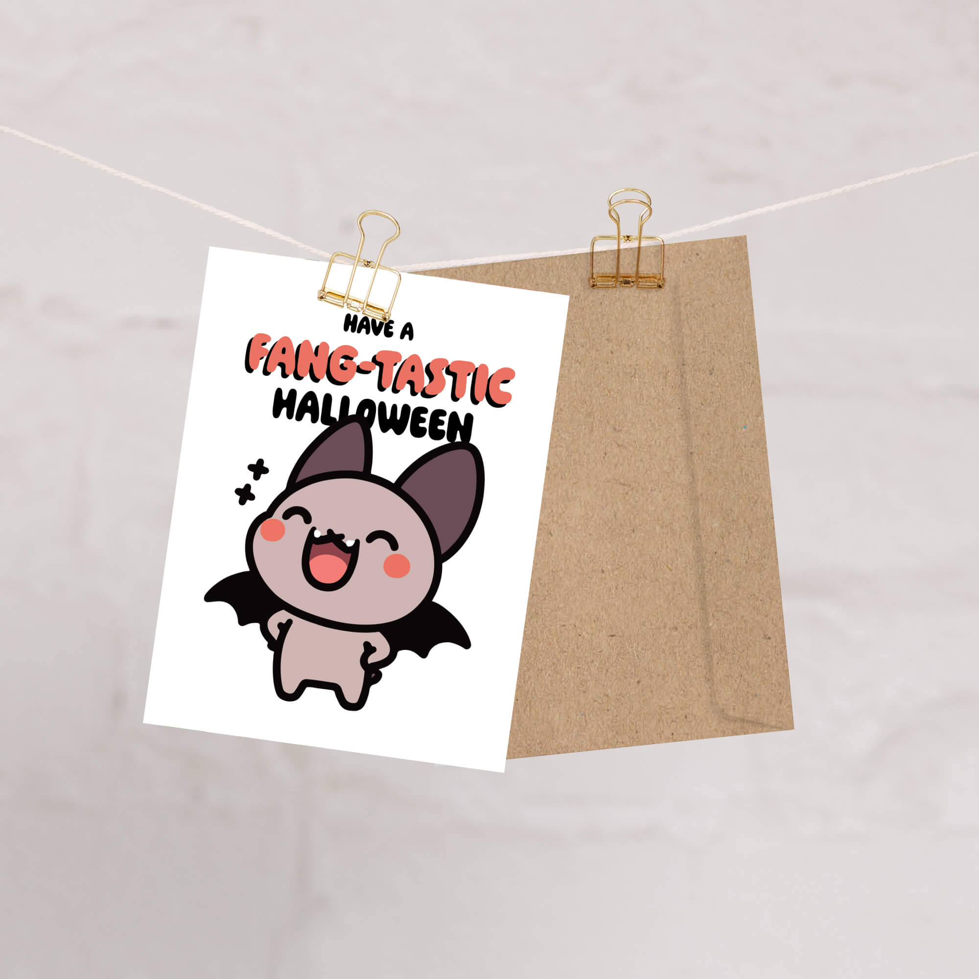 Halloween-themed card with a bat illustration and text on a white background, clipped to a string.