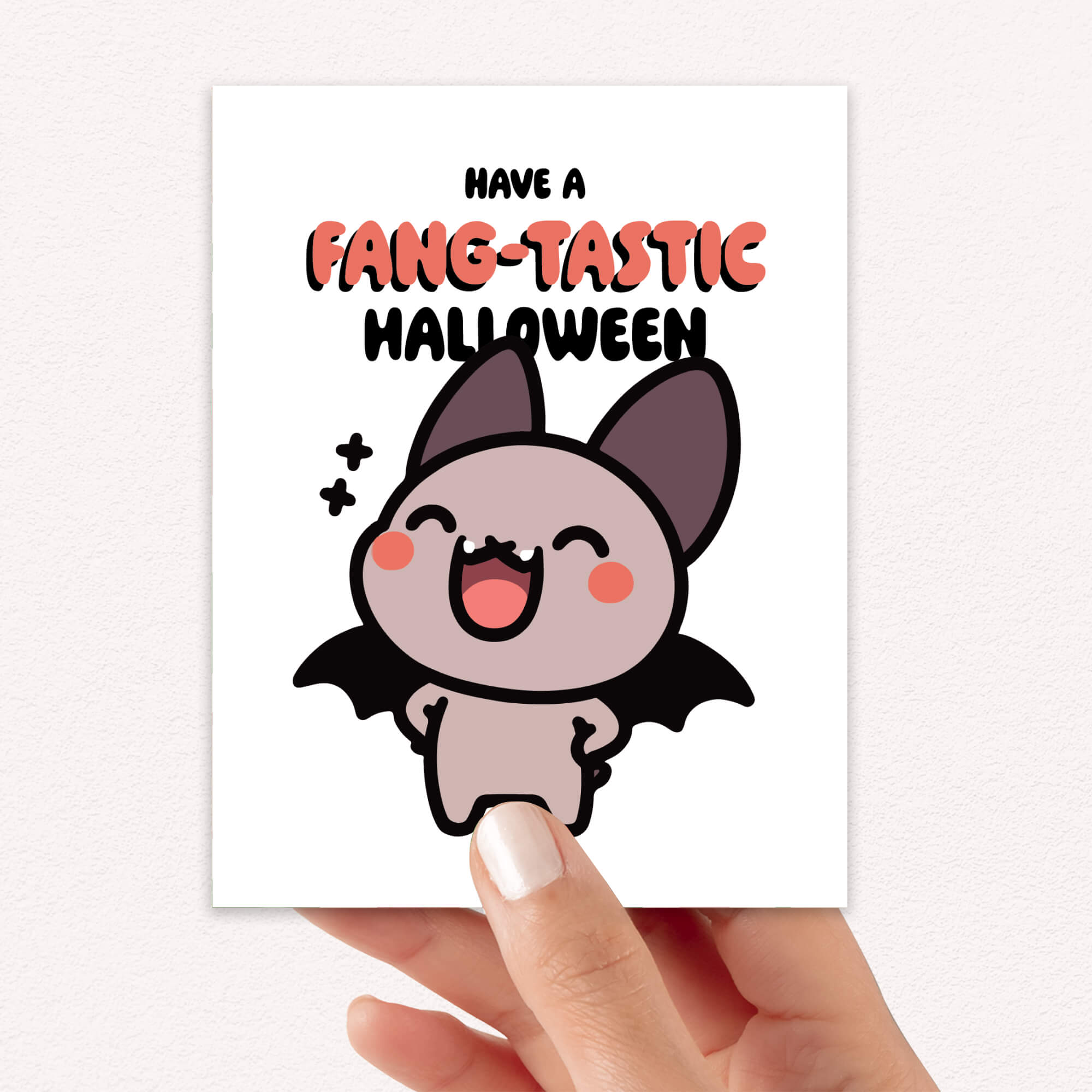 Hand holding a card with a bat illustration and 'Have a Fang-tastic Halloween' text.
