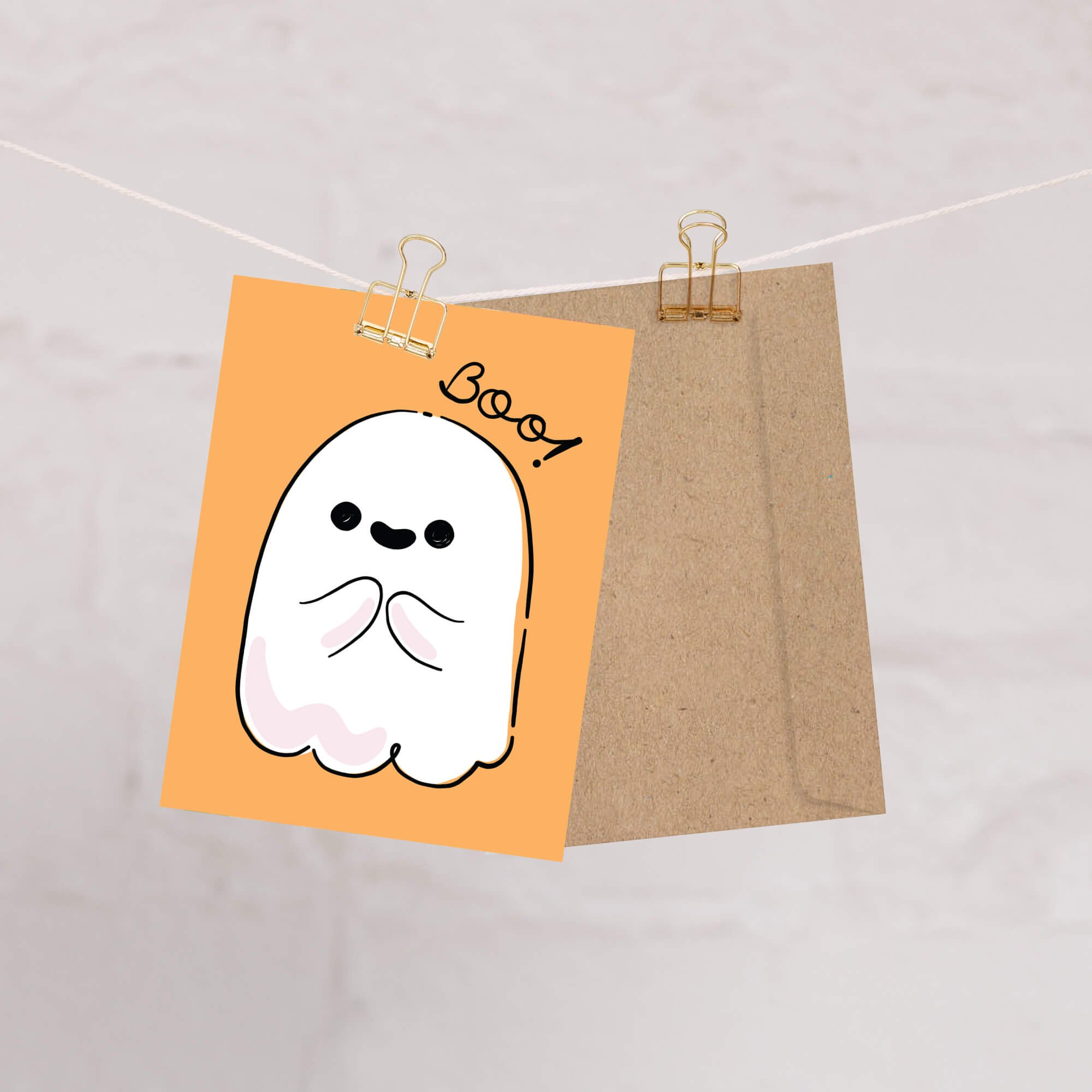 Halloween-themed card with a ghost illustration and 'Boo!' text on an orange background, clipped to a string.