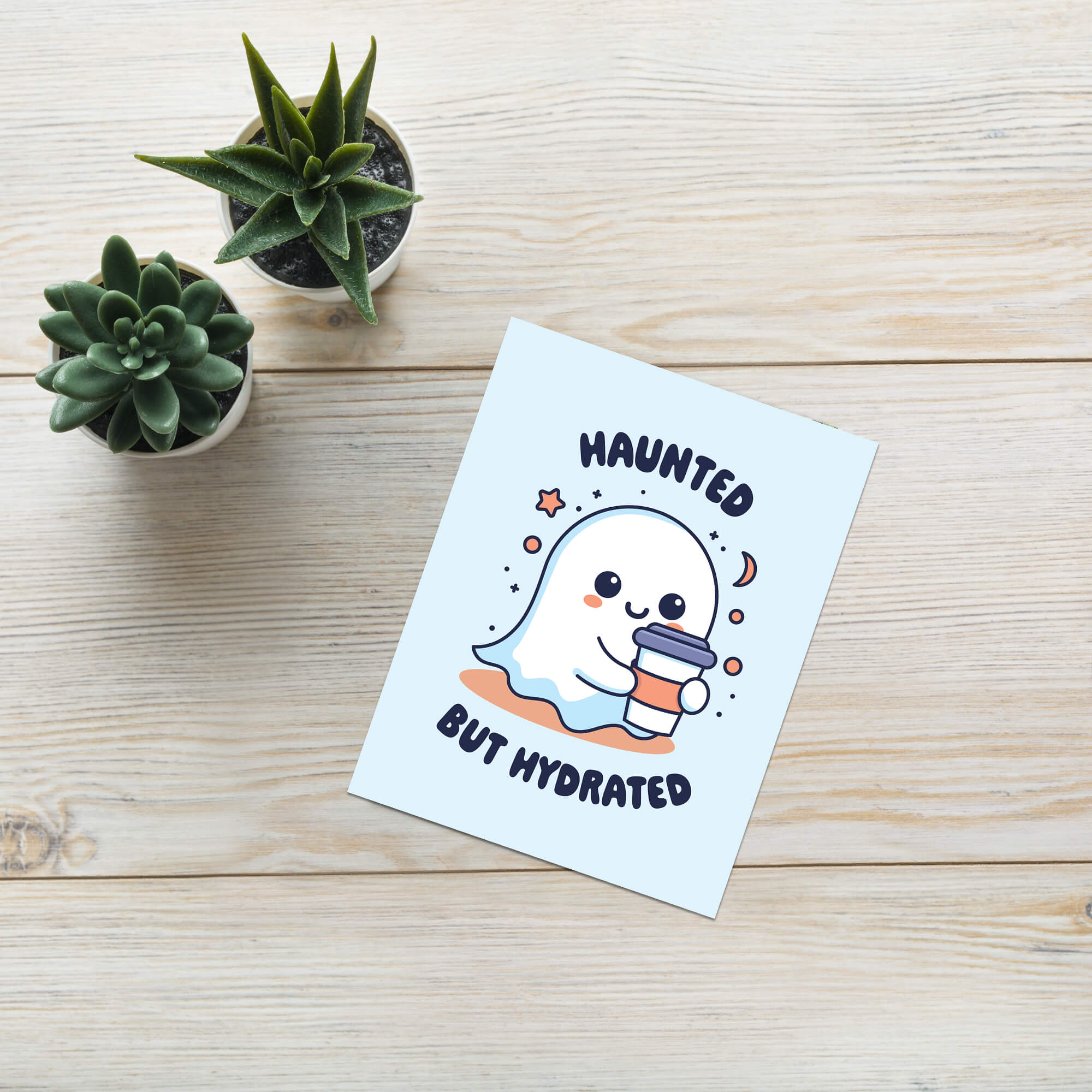 kawaii halloween Greeting card with a ghost holding a cup and 'Haunted But Hydrated' text on a light blue background.