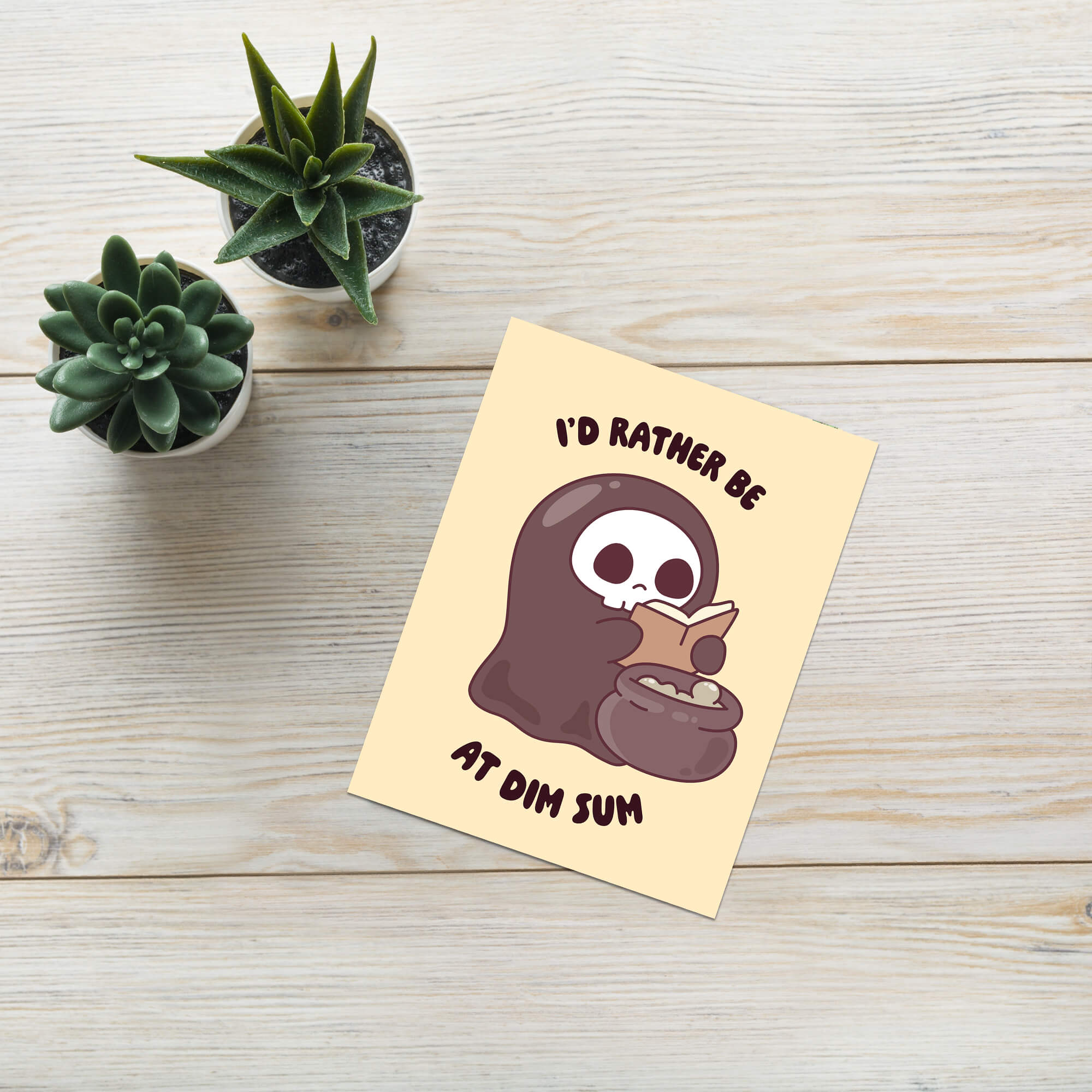 funny halloween Greeting card with a kawaii grim reaper holding a cauldron and text 'I'd rather be at dim sum' on a beige background.