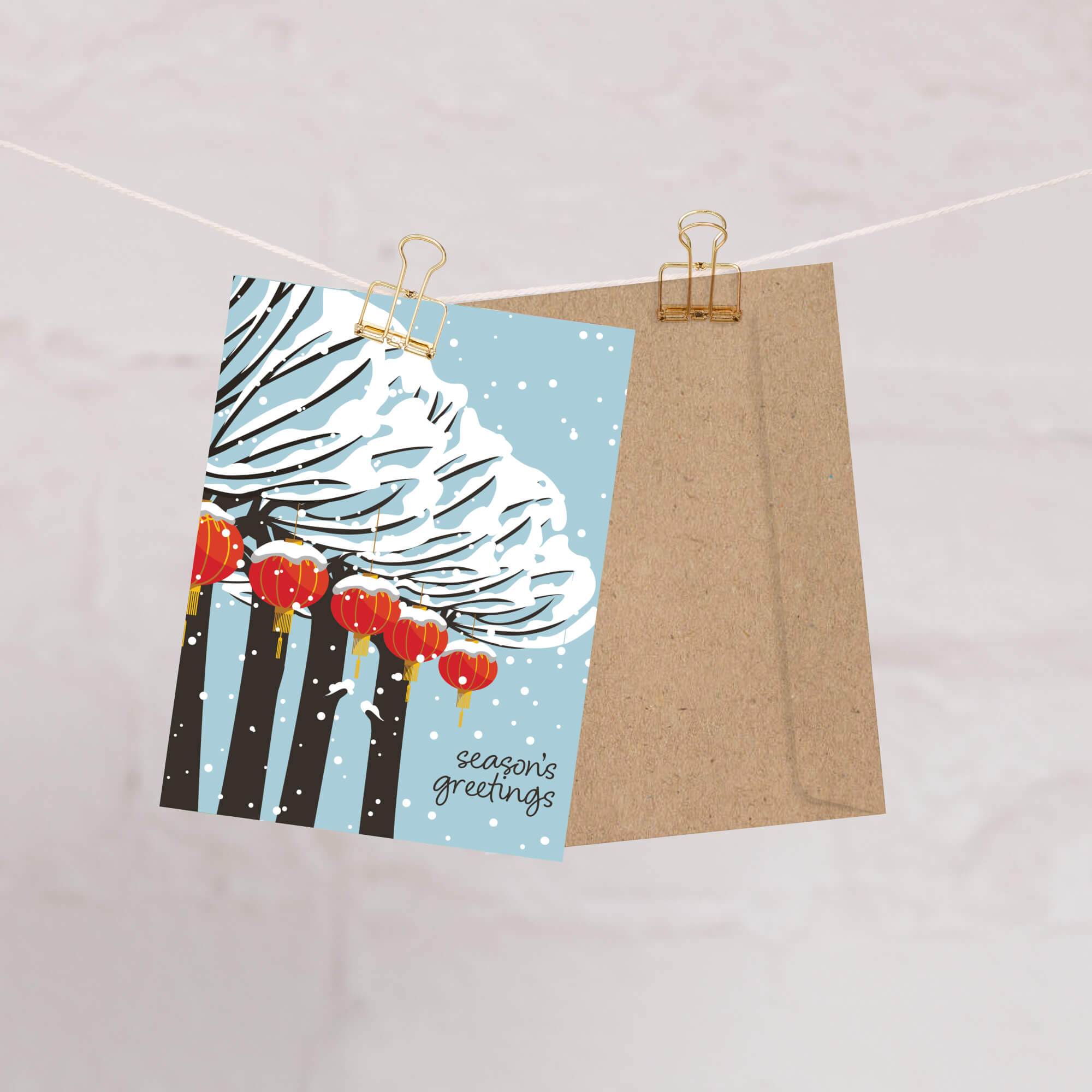 cute christmas card with Snowy trees with hanging asian chinese red lanterns and small “season’s greetings” text.
