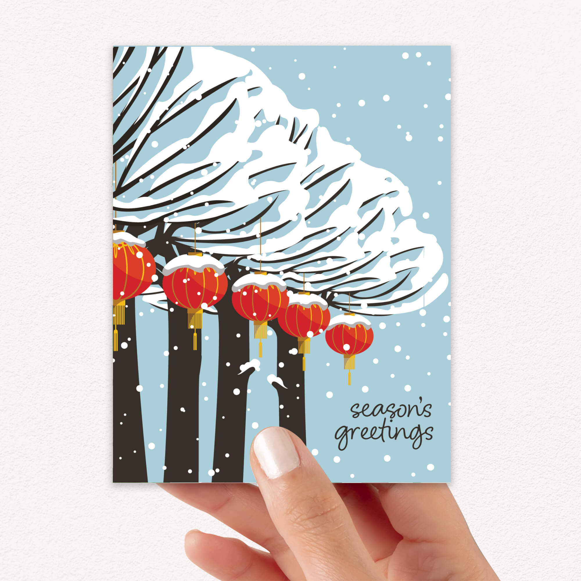 cute christmas card with Snowy trees with hanging asian chinese red lanterns and small “season’s greetings” text.