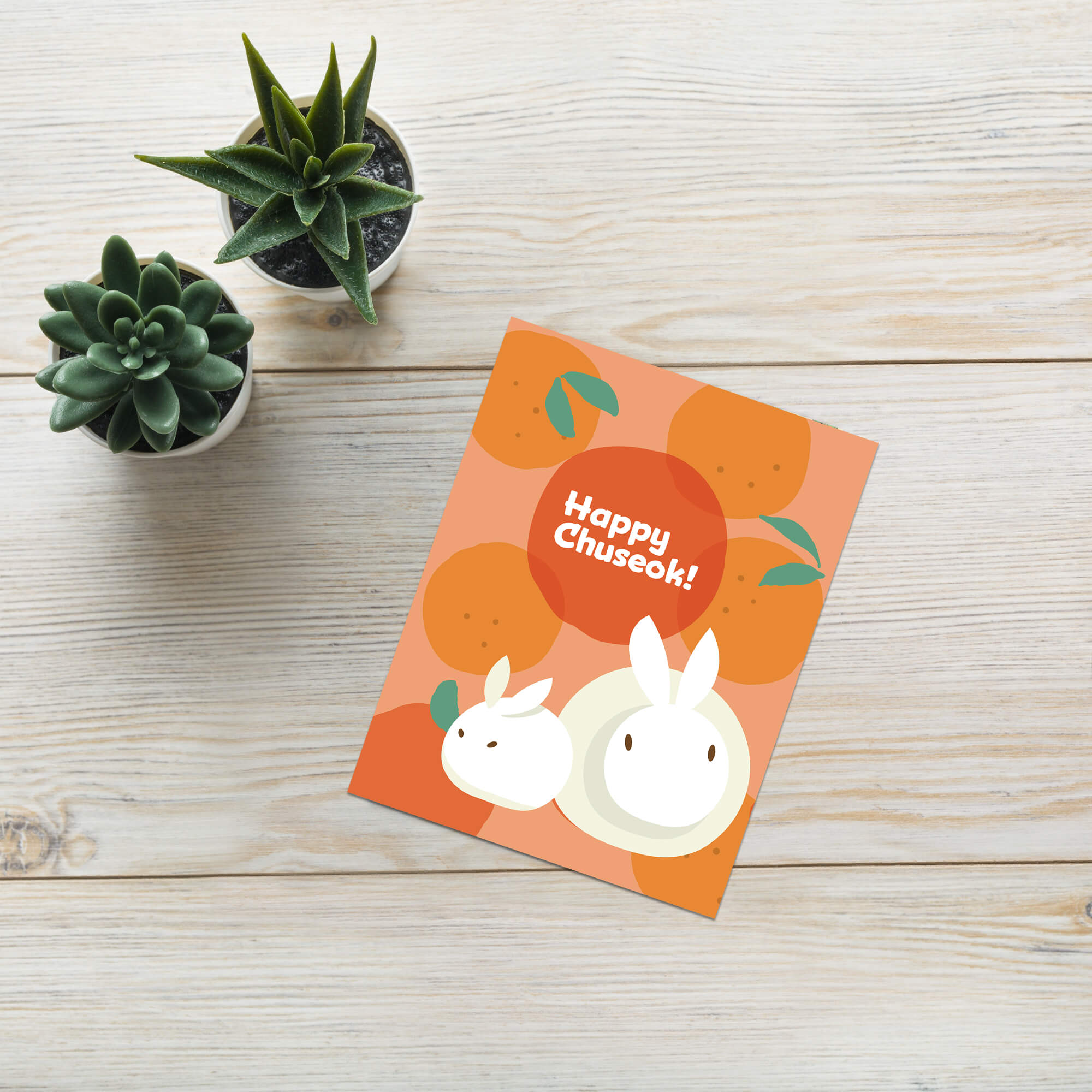 korean inspired Greeting card with rabbits designed as songpyeon and oranges on an orange background, featuring 'Happy Chuseok!' text.