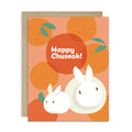 korean inspired Greeting card with rabbits designed as songpyeon and oranges on an orange background, featuring 'Happy Chuseok!' text.