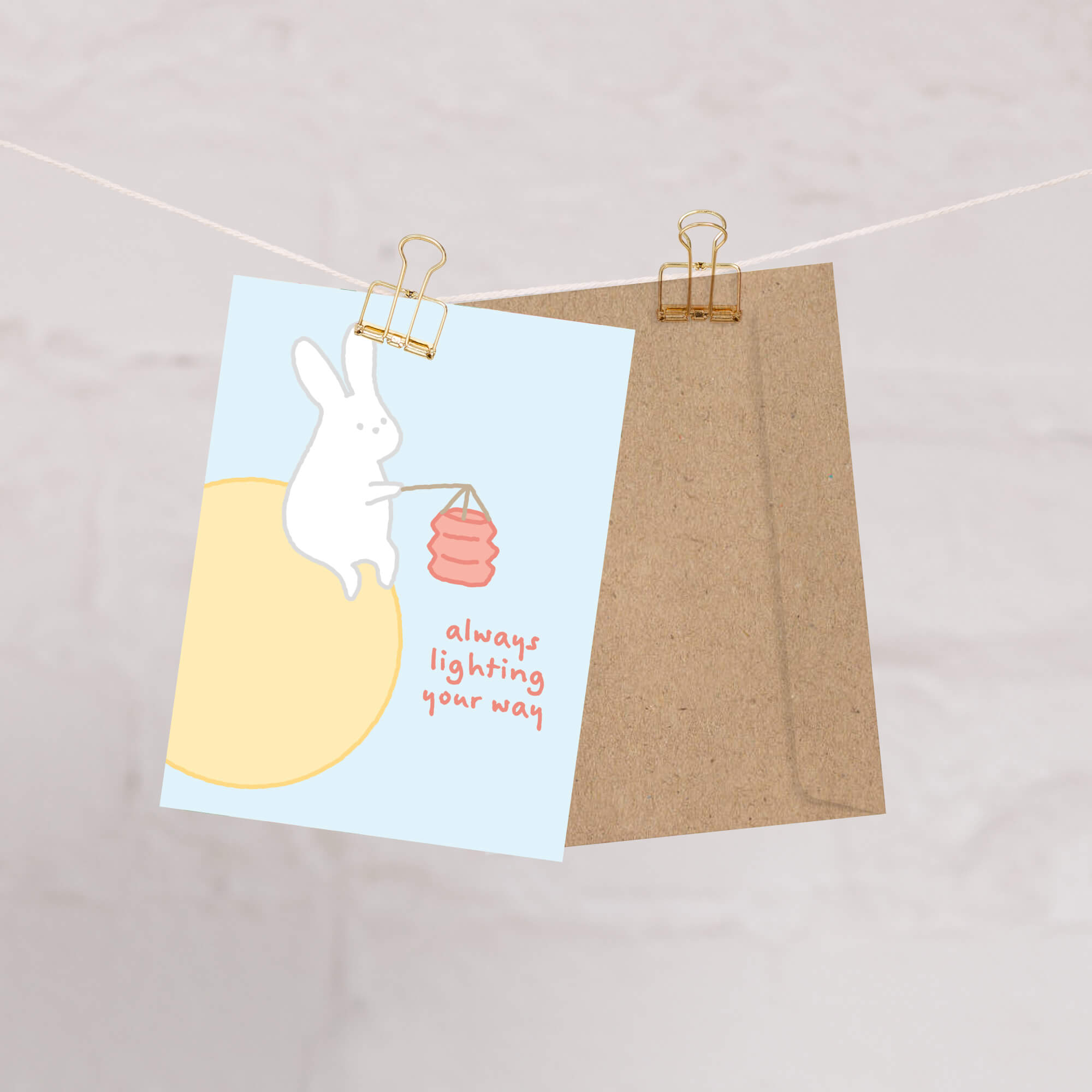 asian inspired Greeting card with a rabbit holding a lantern and text 'always lighting your way' on a light blue background. for mid autumn festival
