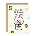 Birthday card with a cartoon rabbit holding a flower, surrounded by hearts and clouds on a light background.