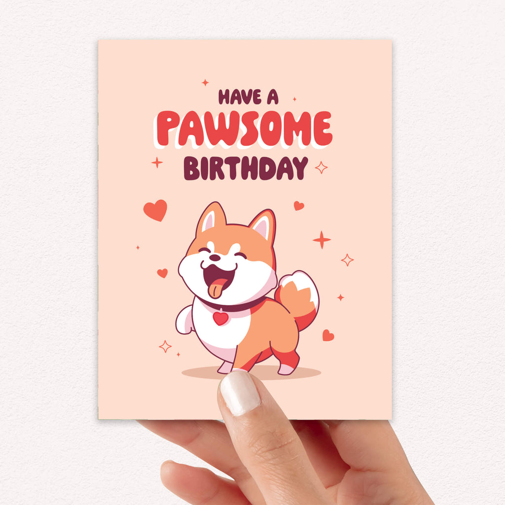 Birthday card with a cartoon dog and 'Have a Pawsome Birthday' text on a light pink background.