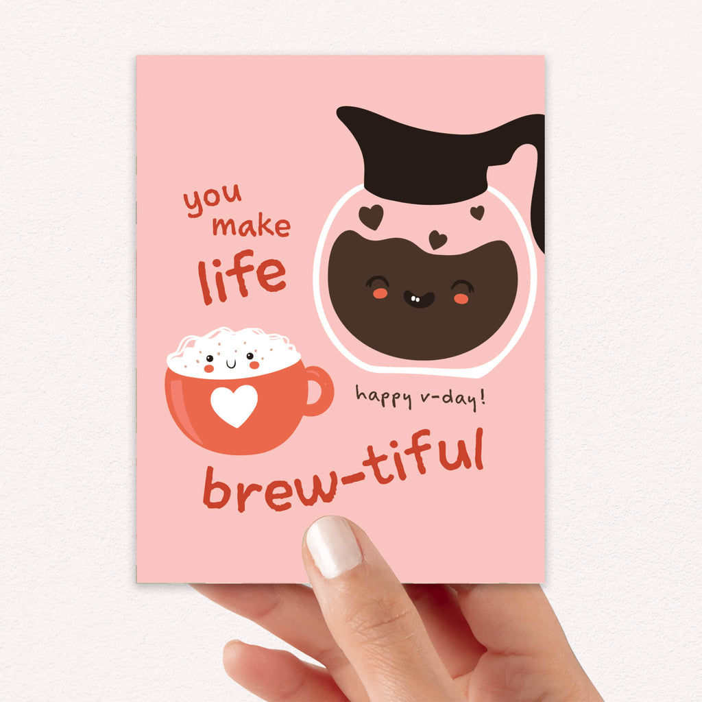 cute valentines day card with a Smiling coffee carafe and heart latte mug on blush pink; text “You make life brew-tiful.”