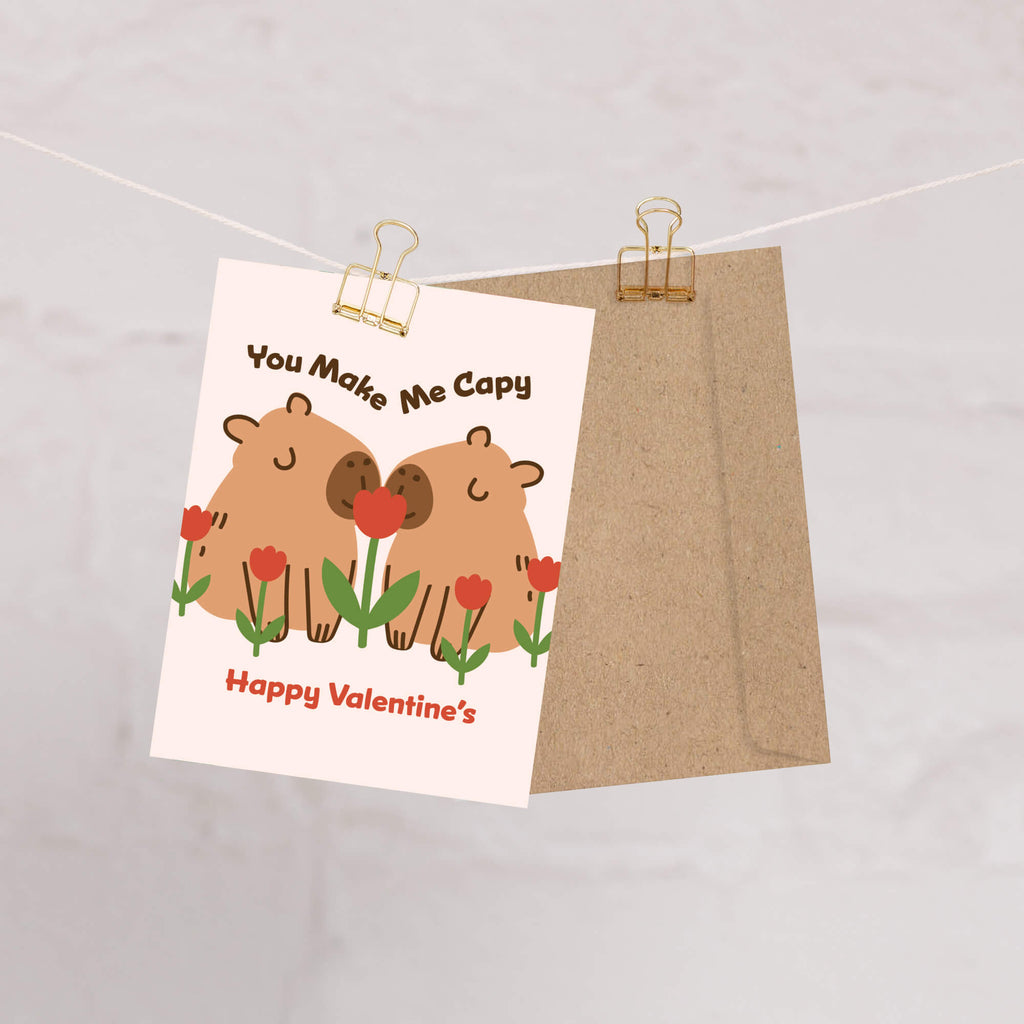 Two capybaras with tulips; curved text “You Make Me Capy” and “Happy Valentine’s.”