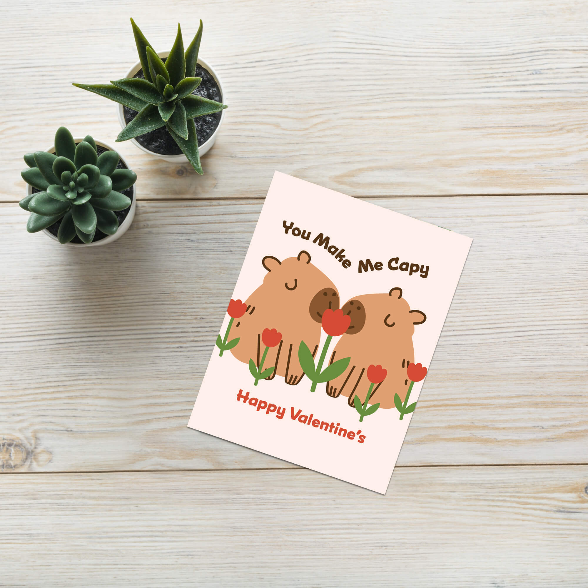 Two capybaras with tulips; curved text “You Make Me Capy” and “Happy Valentine’s.”